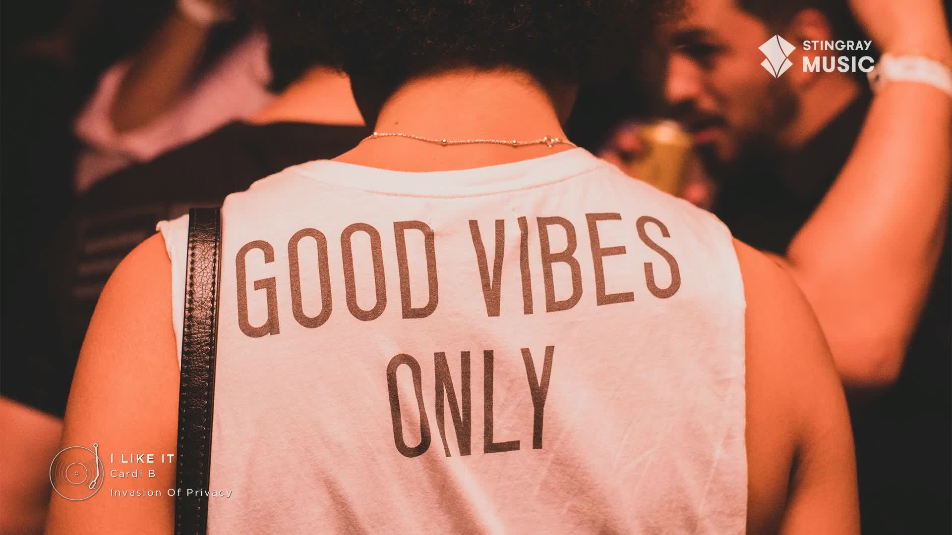 A person's back is turned, with the words "GOOD VIBES ONLY" printed on their white tank top.  The Stingray Music logo is visible, and the music is probably pumping in this crowd.
