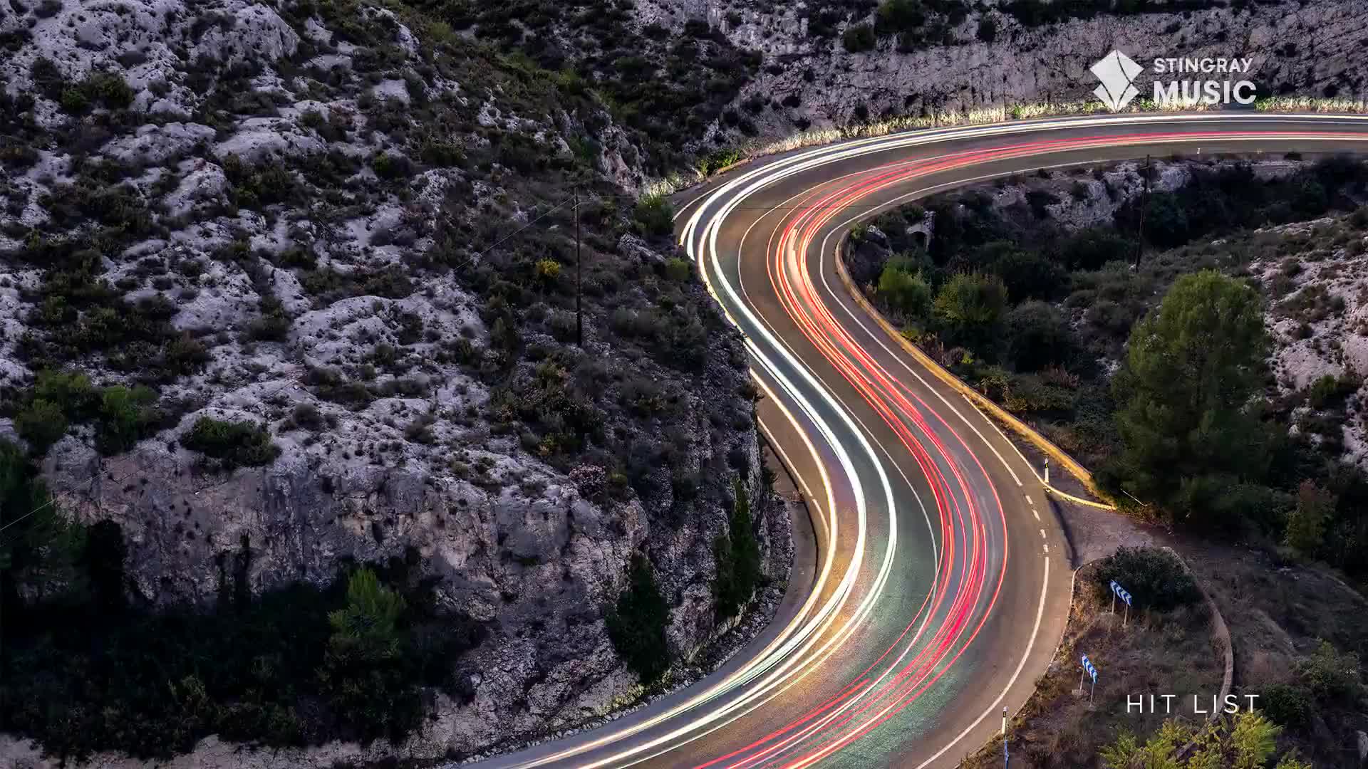 Headlights streak down the winding road, leaving trails of white and red light in their wake. The Stingray Hit List in Canada is likely playing in the background, as the cars speed by.
