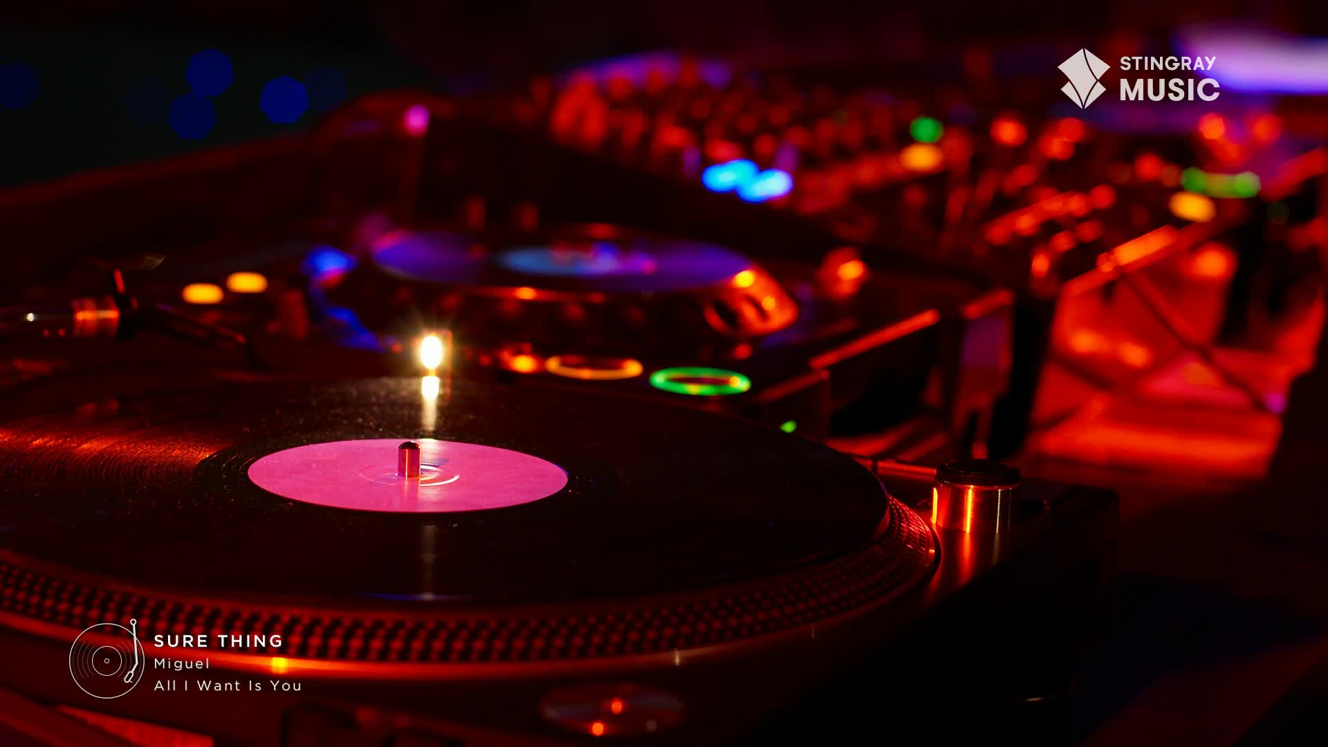 A vinyl record spins on a turntable, the center label a bright pink, and the whole scene bathed in red light. The Stingray Music logo is visible, and the track "Sure Thing" by Miguel is about to drop on the Canadian Hit List.
