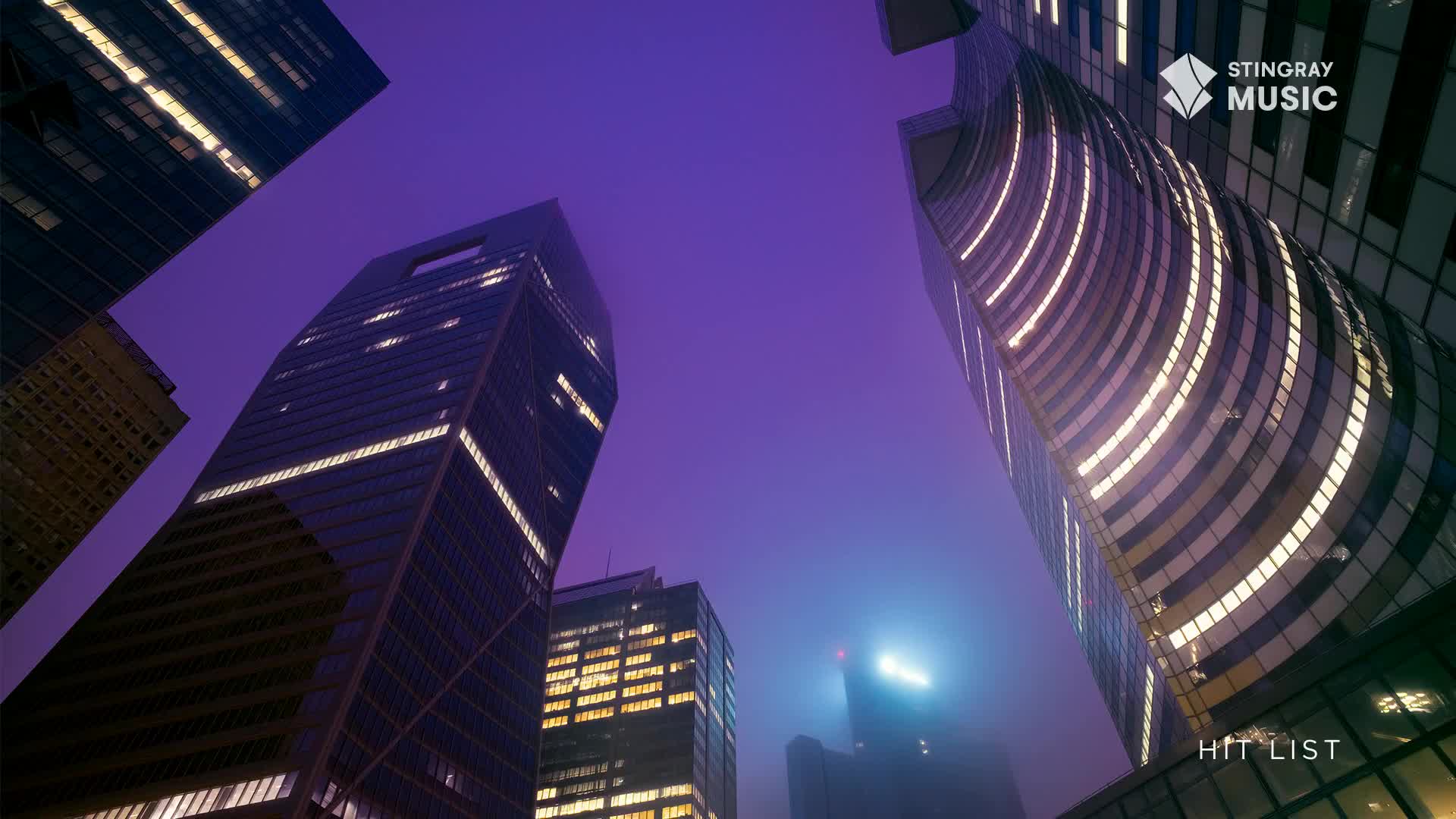 The imposing skyscrapers of a Canadian city pierce a deep purple sky. Illuminated windows and curved lines of light reflect the Stingray Hit List vibe.

