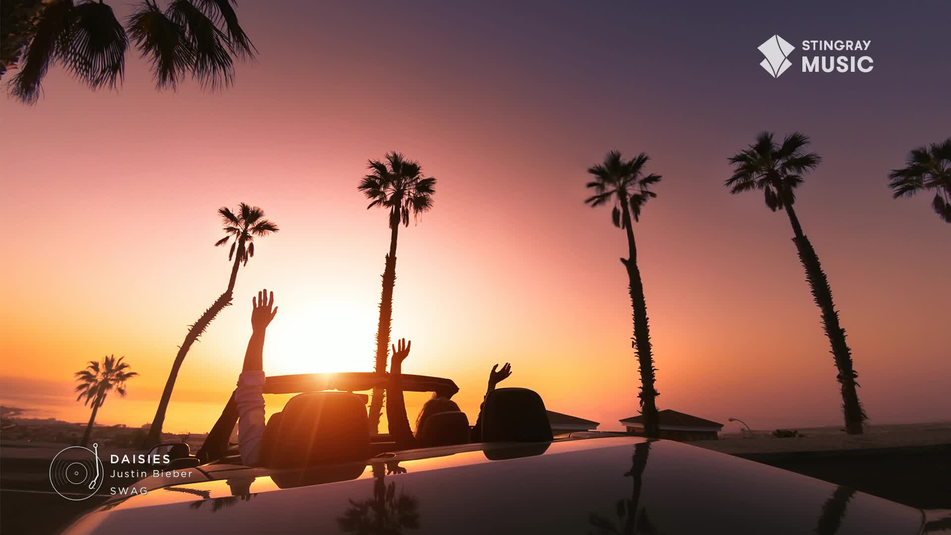 A convertible cruises down a coastal road, its occupants silhouetted against the sunset, arms raised. The sky is ablaze with color, framed by swaying palm trees, a perfect backdrop for a Stingray Hit List video from Canada.
