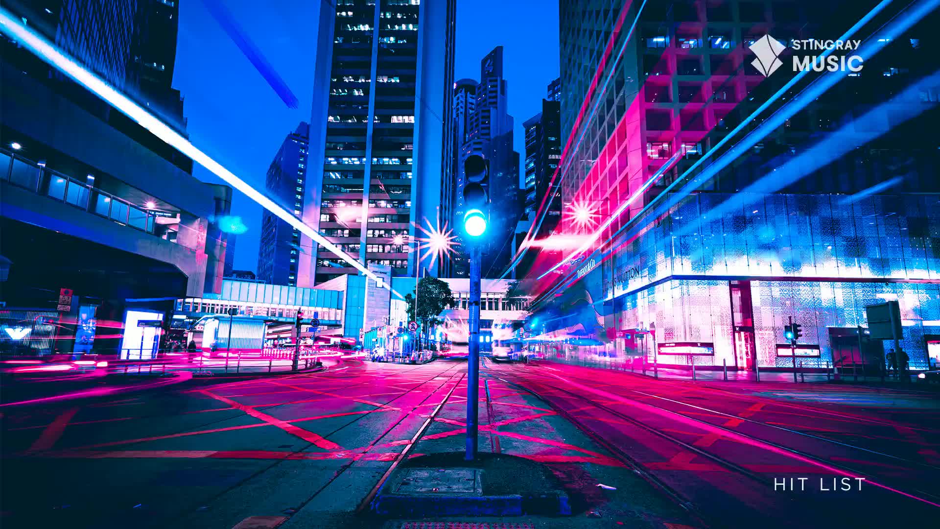 Neon streaks of light, likely from vehicles, cut across the road, creating vibrant pink and blue lines. The traffic light glows a steady blue, a beacon in this urban scene, perhaps a Stingray Hit List selection from Canada.
