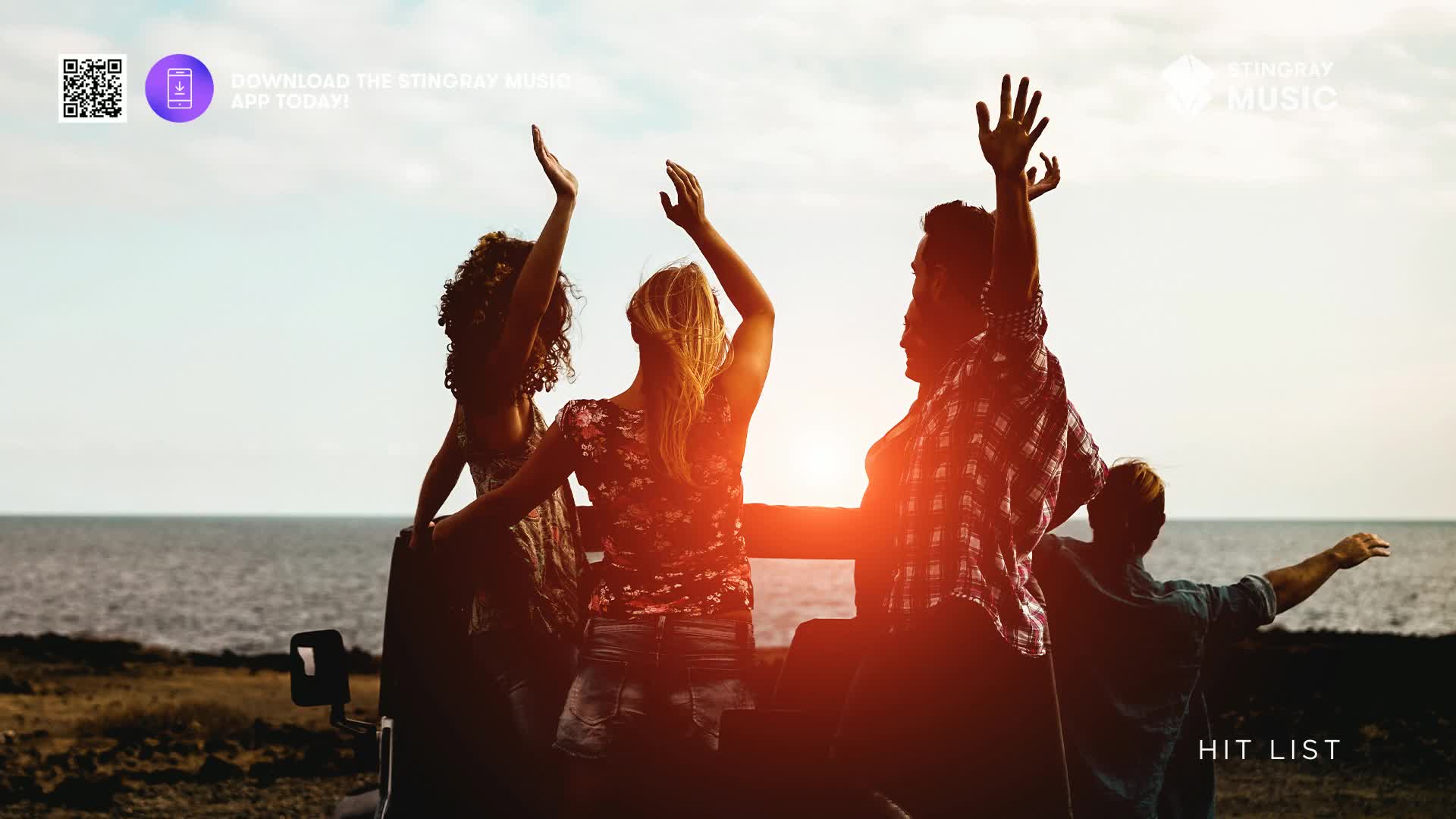 Four friends stand in the back of a vehicle, arms raised toward the sun. The scene feels like a Stingray Hit List commercial, with the ocean in the background.
