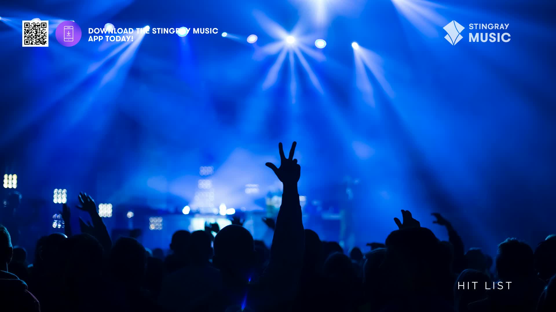 The crowd's arms are raised, illuminated by intense blue stage lights. Someone's hand is making a peace sign, and the "Hit List" from Stingray Music is blasting through the speakers.
