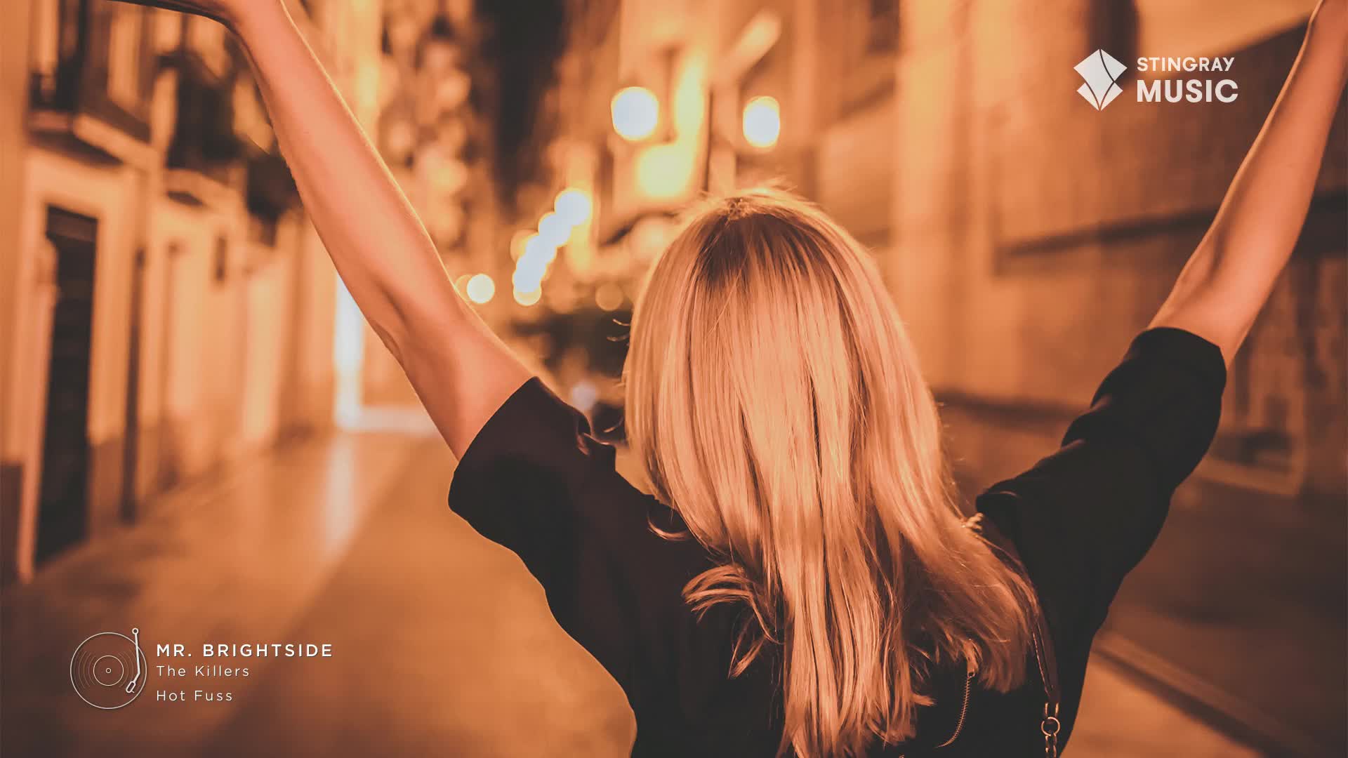 A woman with long blonde hair stands with her arms raised, seemingly celebrating. The Stingray Hit List logo and the song "Mr. Brightside" by The Killers are visible, suggesting a connection to Canadian music.
