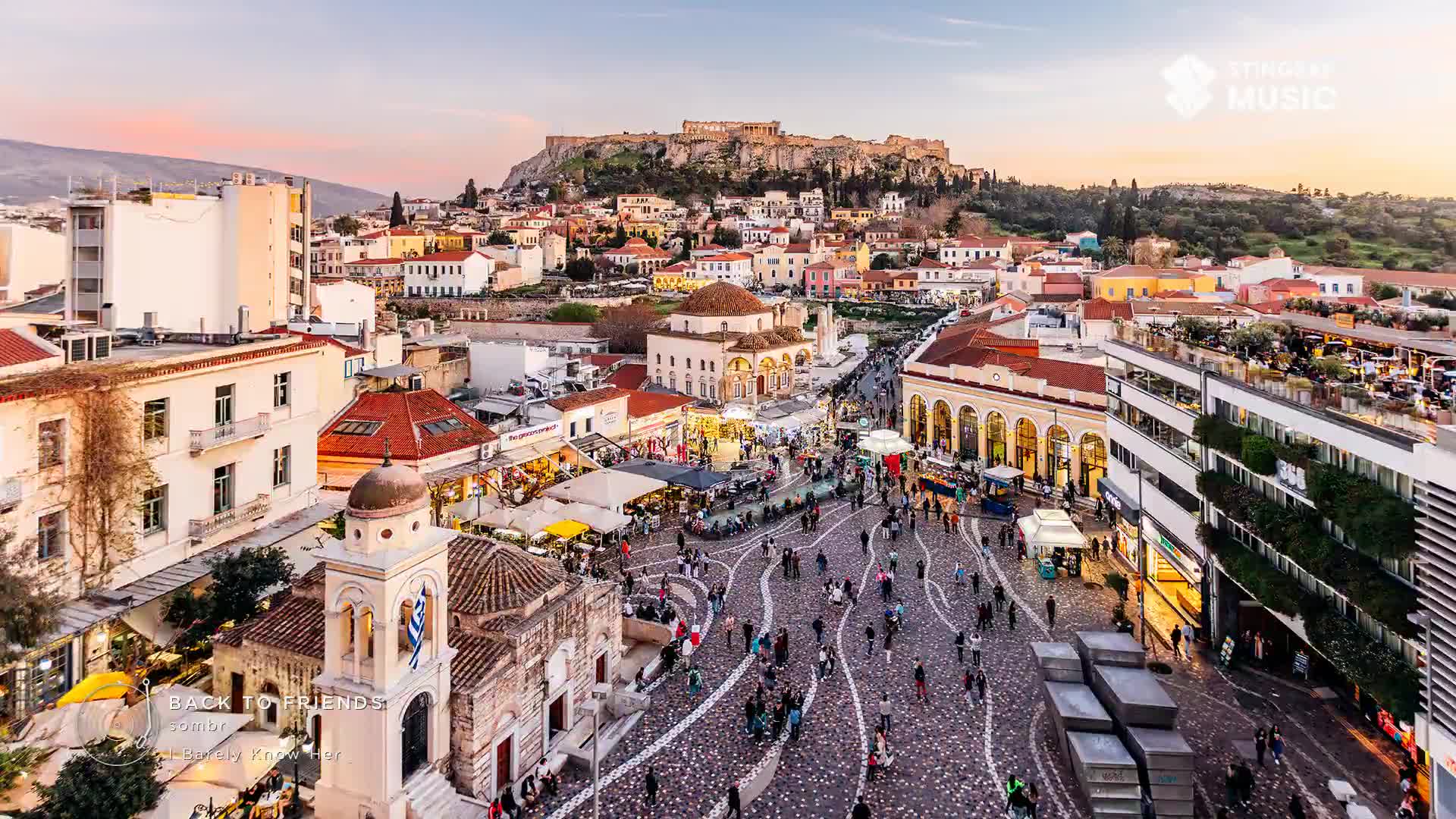 People are strolling through a bustling plaza, their footsteps echoing on the patterned cobblestones. Above, the ancient Acropolis stands silhouetted against a soft, twilight sky.