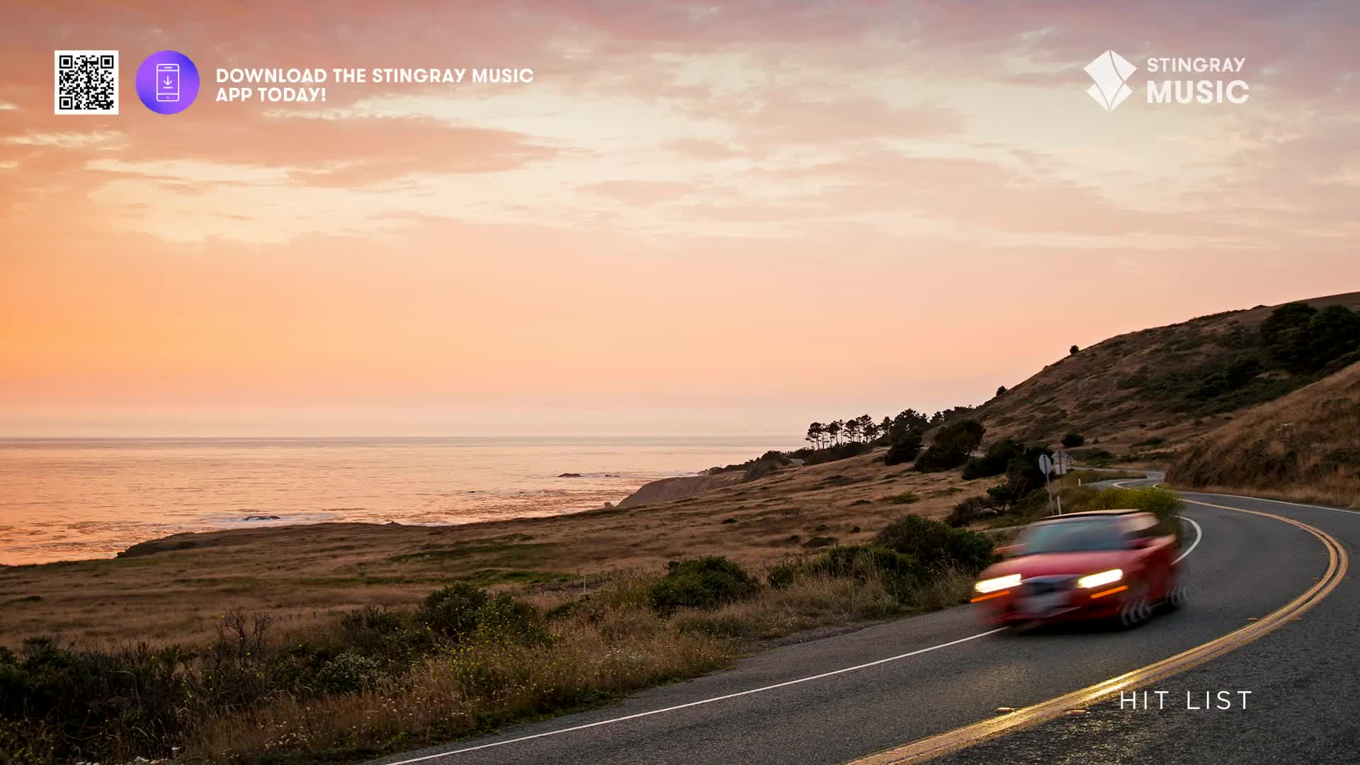A red car speeds around a coastal highway curve as the sun sets over the Pacific. The Stingray Music Hit List plays as the car heads toward the horizon.