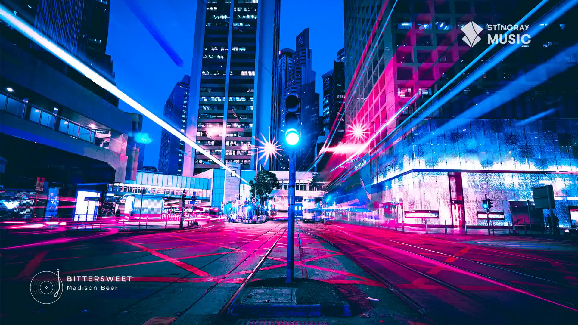 Headlights streak past in vibrant pink and blue streaks, painting the wet asphalt of a Canadian city street. A traffic light glows an electric blue, its signal a stark contrast to the neon glow of the surrounding buildings.