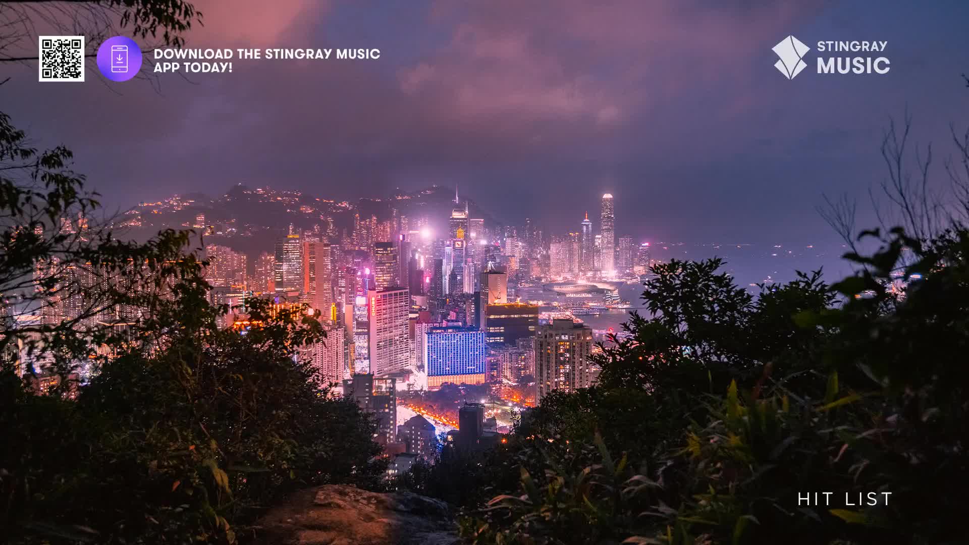 The city lights of Hong Kong stretch out before me, a vibrant tapestry under the twilight sky.  The Stingray Music Hit List is playing, a soundtrack to this stunning panorama.