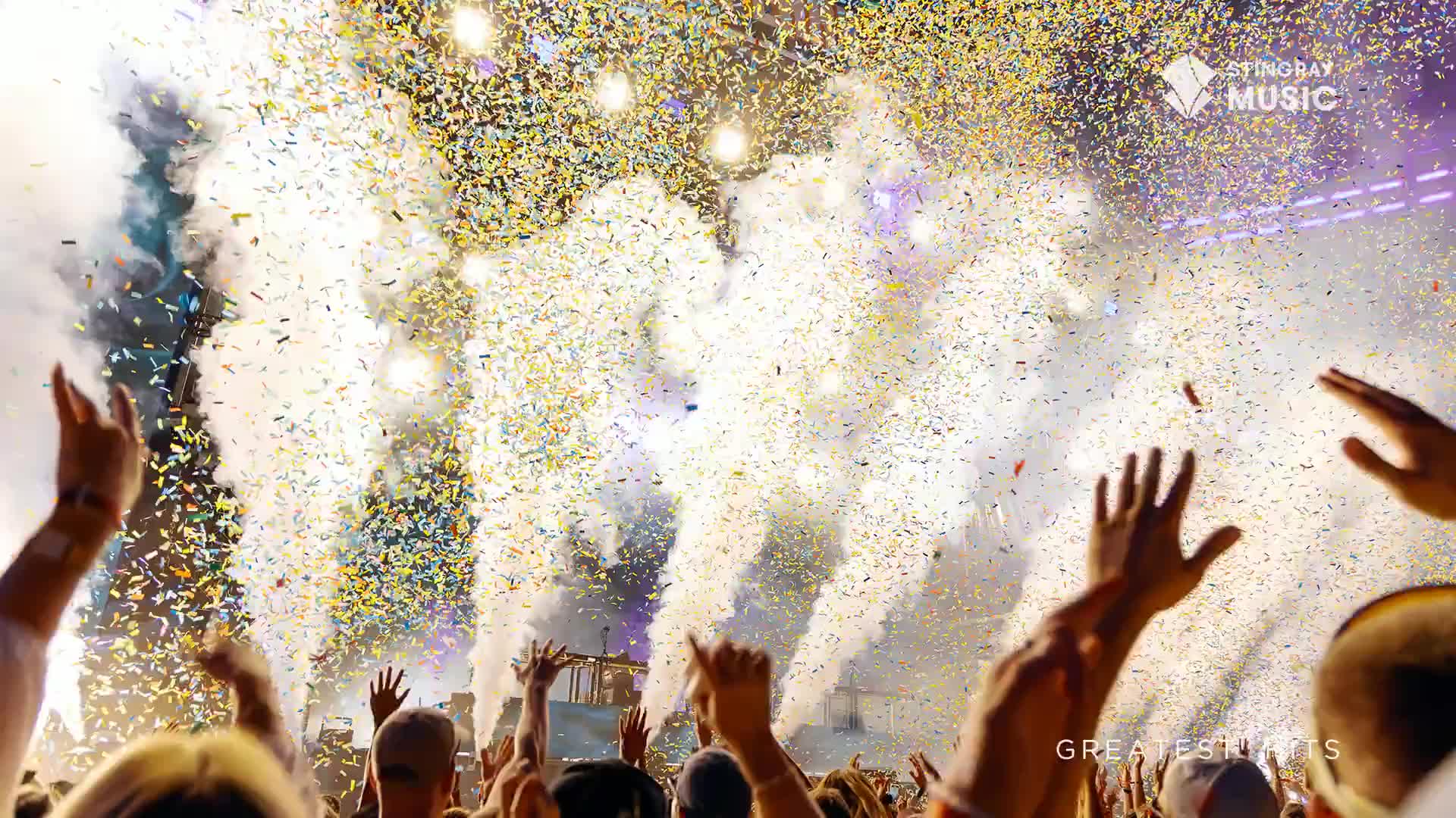 Confetti rains down, mixing with plumes of white smoke as the crowd's hands reach up. The energy is electric, and the music from Stingray Holiday Hits is pumping through the speakers.
