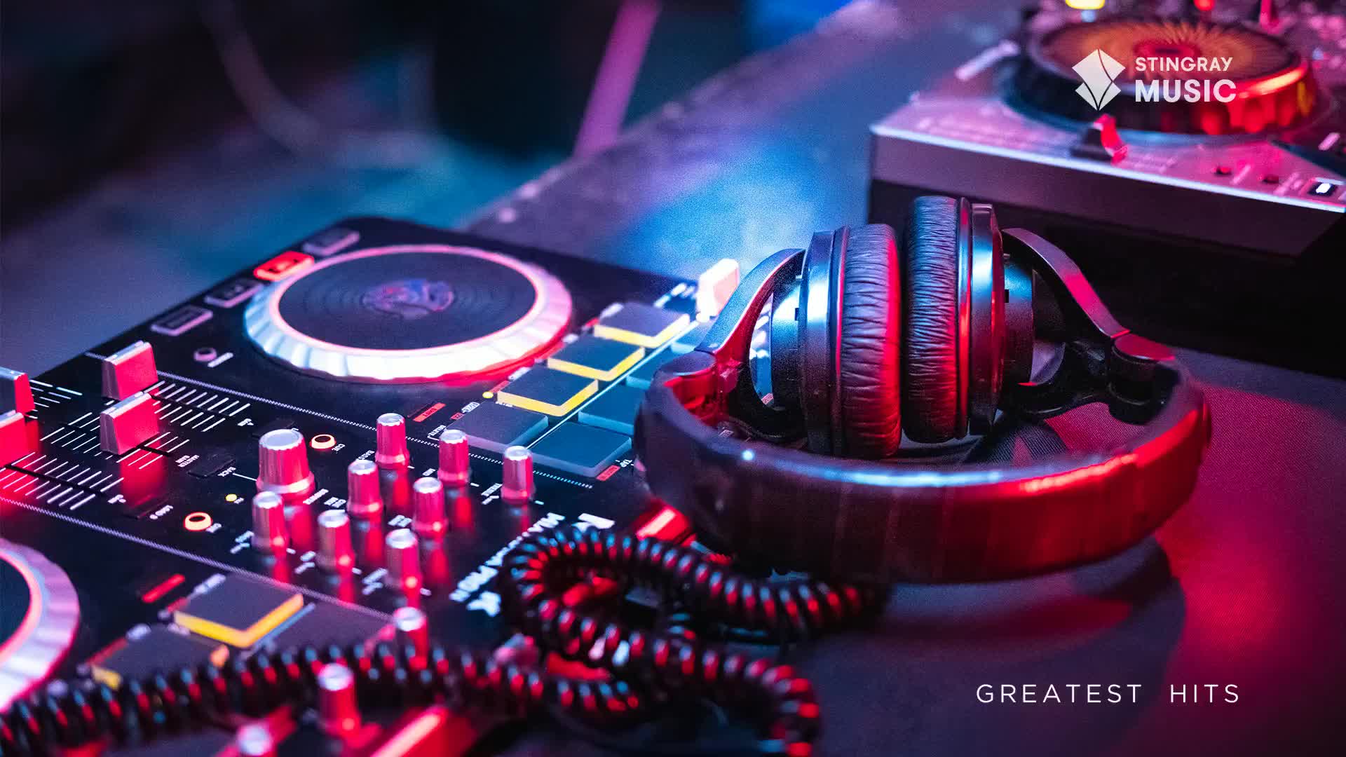 Headphones rest on a stand, illuminated by red and blue light, next to a mixing board.  The Stingray Music logo sits on a nearby control panel, promising holiday hits from Canada.
