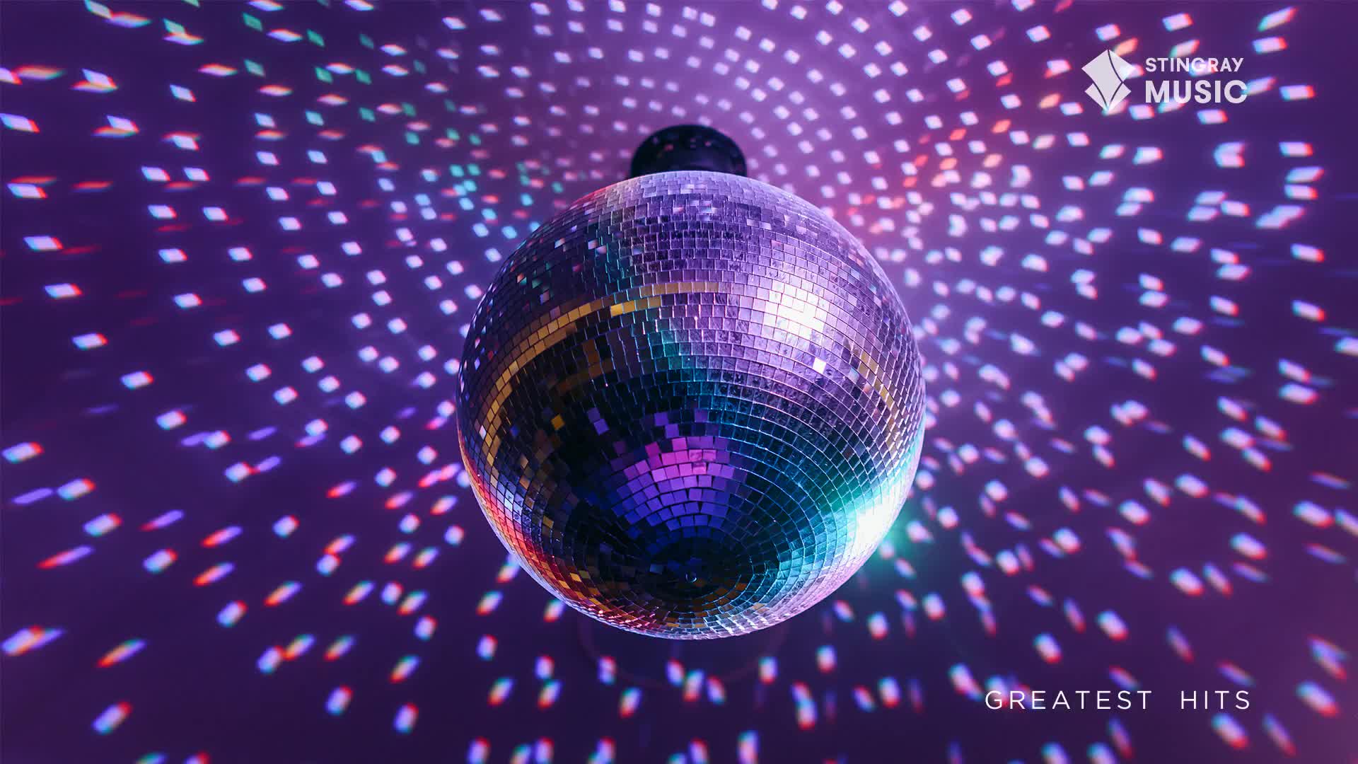 A mirrored disco ball hangs, reflecting light onto a purple background.  Tiny, colorful spots of light dance across the surface, a perfect visual for a Stingray Holiday Hits playlist.
