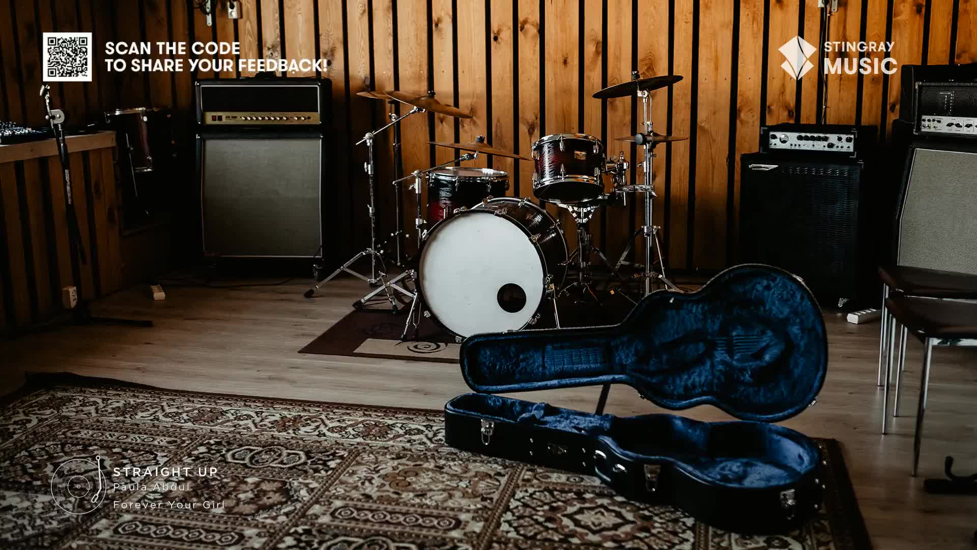An open guitar case sits on the floor, ready for the next song. A drum kit and amps fill the room, likely for a recording session for Stingray Holiday Hits in Canada.
