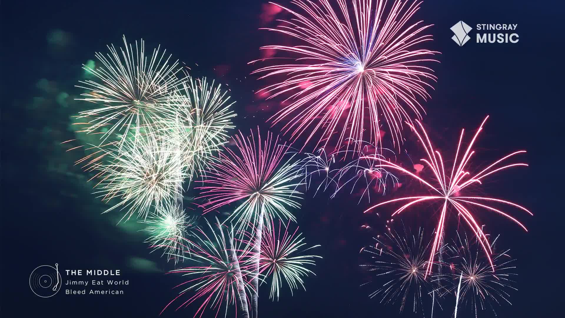 Green and pink bursts bloom in the dark sky, their trails of light fading. The display is part of a Stingray Holiday Hits celebration, a fitting accompaniment to the music.
