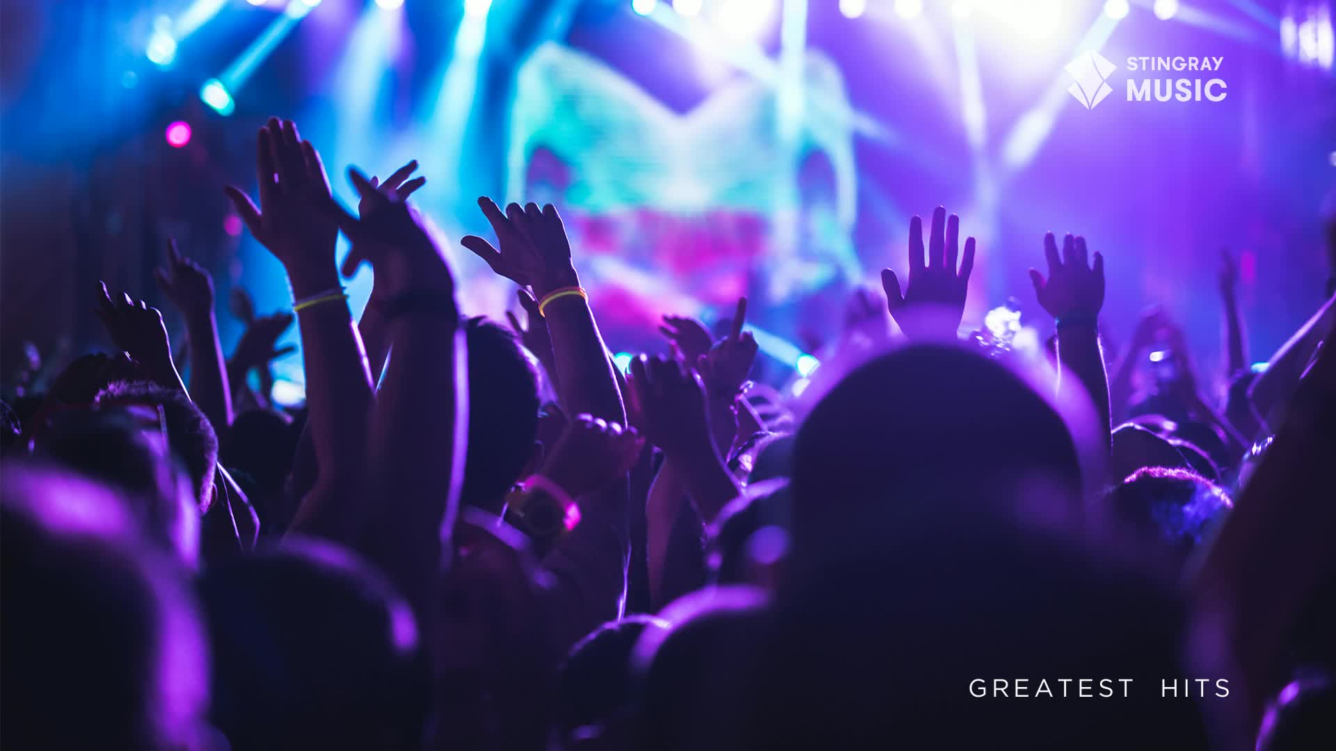 Arms are raised, illuminated by the stage lights, as the crowd moves to the music. The Stingray Music logo and "Greatest Hits" are visible, suggesting a live show in Canada.
