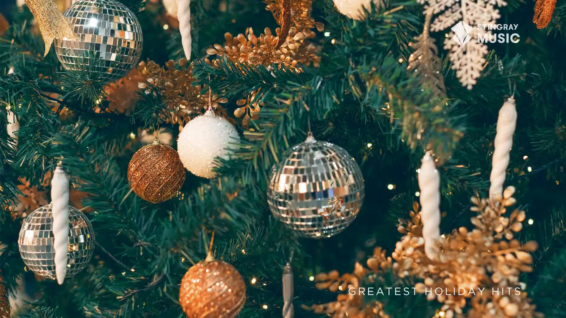 A Christmas tree, festooned with disco ball ornaments and glittering gold accents, fills the frame. The Stingray Holiday Hits logo from Canada is subtly placed in the corner.

