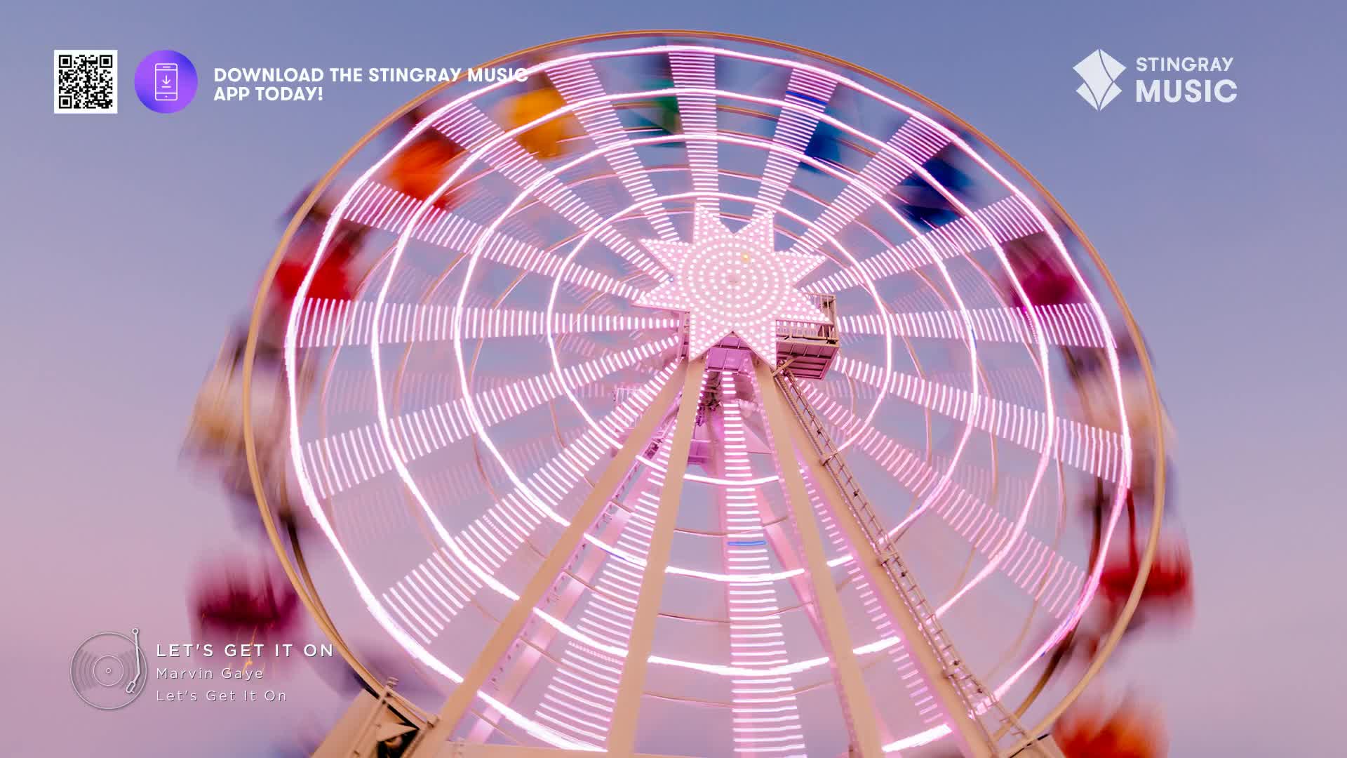 The Ferris wheel spins, its lights a streaky pink against the twilight sky.  A few colourful gondolas are visible as they pass.