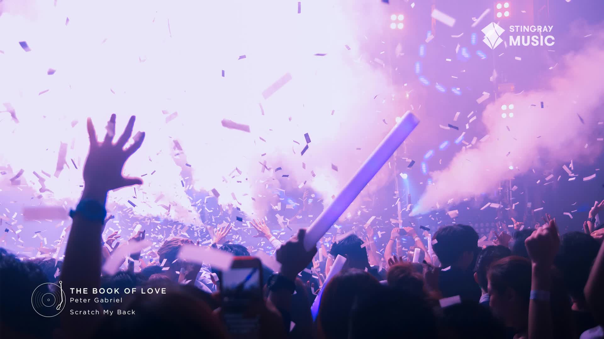 Confetti rains down on a packed crowd, hands reaching up as a purple light stick waves. The air is thick with fog and the energy of a Canadian holiday party.