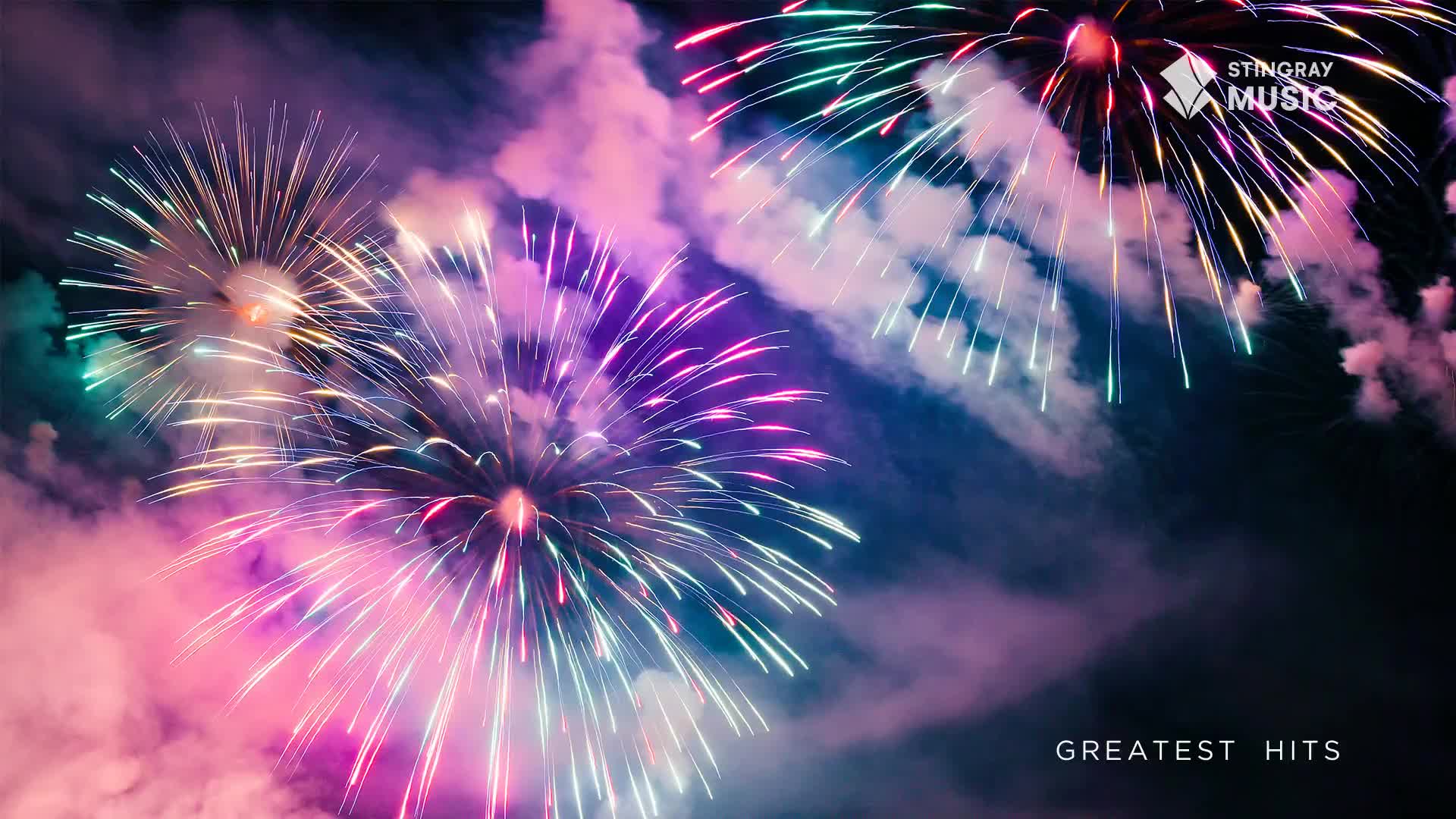 Bright bursts of pink and teal fireworks explode against the night sky, trailing smoke that catches the light. This is the kind of spectacle you'd expect on Canada Day, a real Stingray Holiday Hits moment.