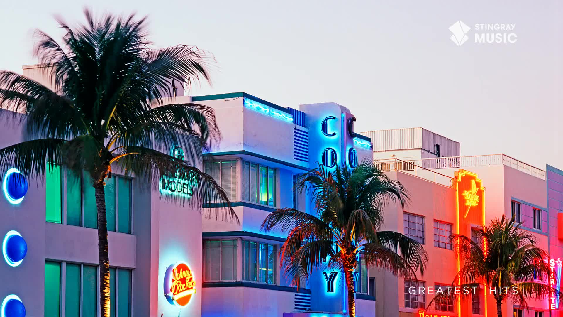 Palm trees sway in front of Art Deco buildings lit by neon signs. A bright orange lightning bolt sign illuminates the building to the right.