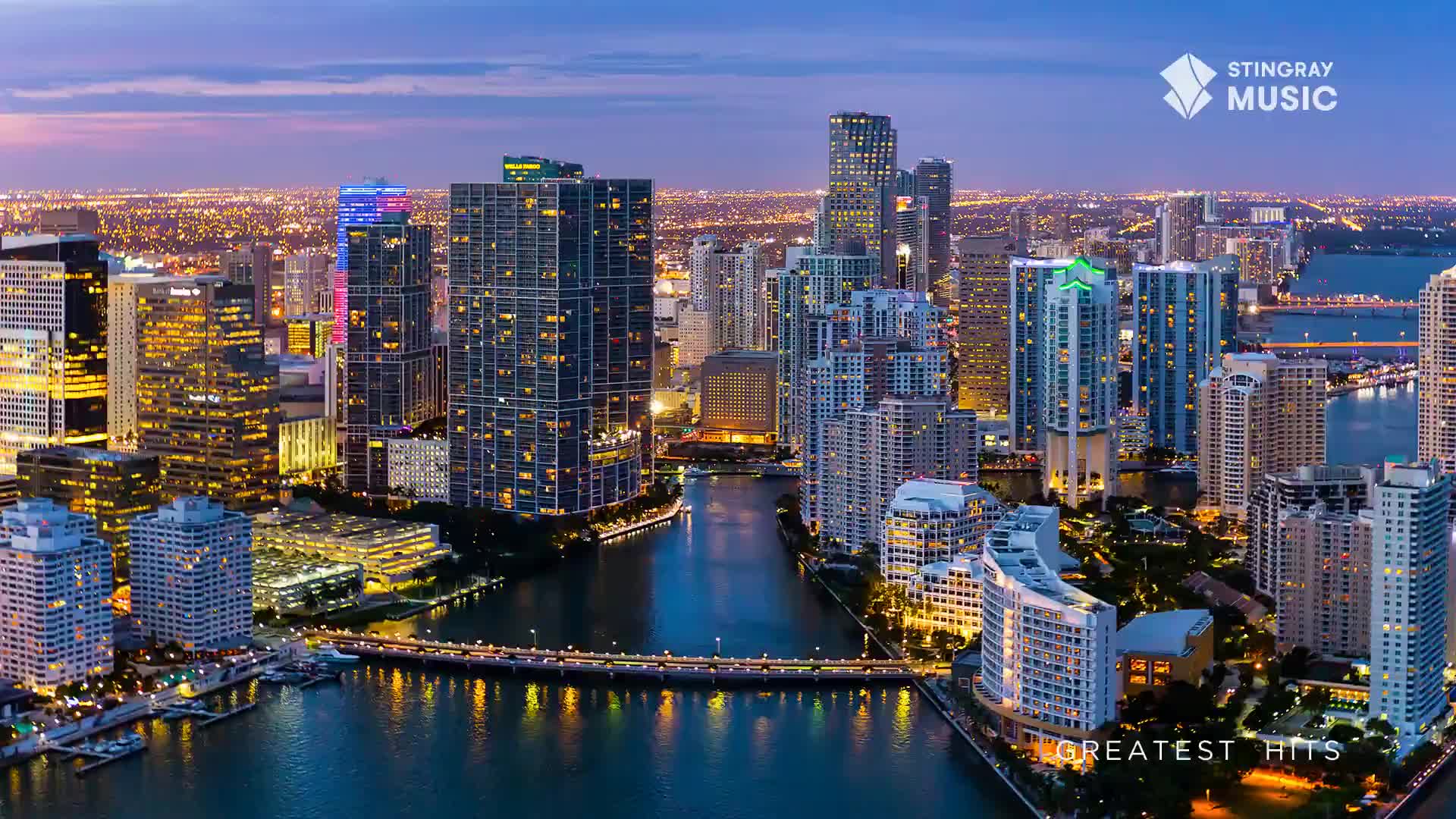 The city lights stretch out before me, a vast network of glowing windows and streetlamps. A river cuts through the heart of it all, reflecting the twilight sky and the illuminated buildings that line its banks.