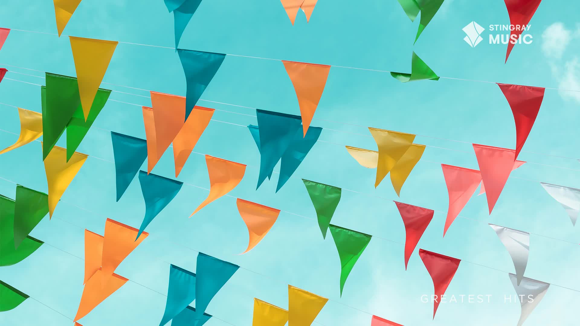 A gentle breeze lifts strings of colorful pennants against the bright Canadian sky. These festive flags, like those seen at a Stingray Holiday Hits celebration, dance and flutter overhead.