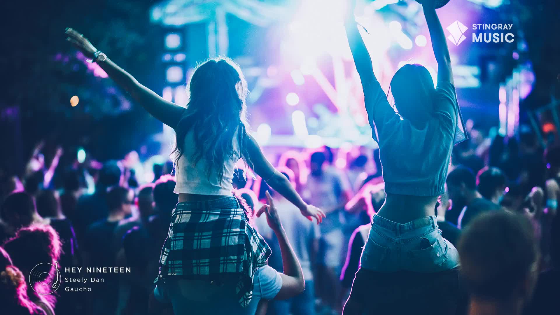 The crowd is alive with the energy of a summer festival in Canada, hands reaching for the sky as "Hey Nineteen" by Steely Dan plays. Lights pulse, reflecting off the faces of people lost in the music.