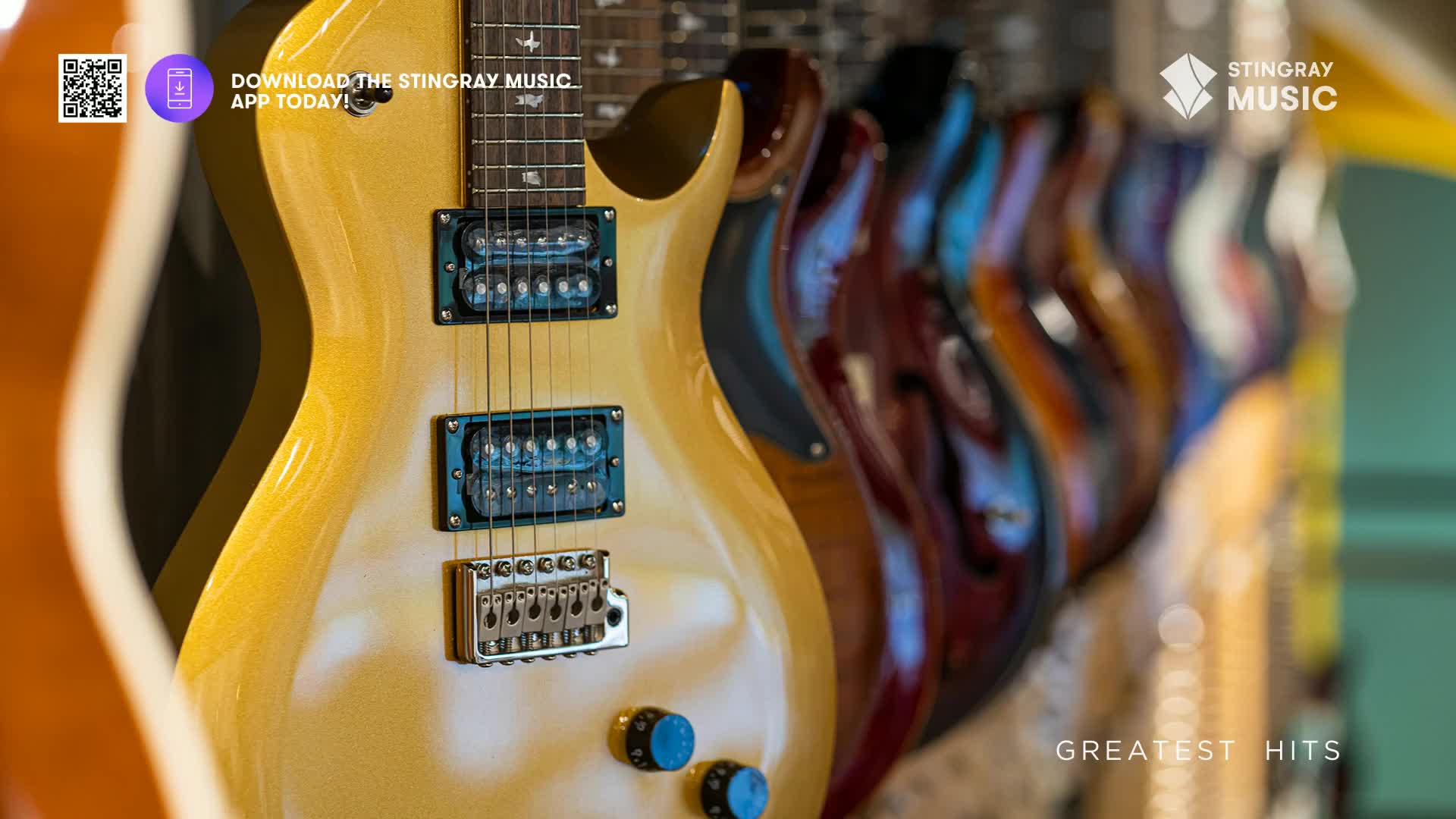 A row of electric guitars, their bodies gleaming in shades of cream and rich wood tones, hang in a shop. The Stingray Music logo is visible, suggesting a connection to their holiday hits collection.