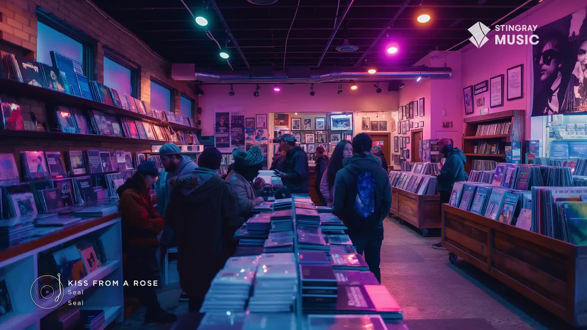 A group of people browse through records in a dimly lit store, the shelves packed with albums. The air hums with the sound of Seal's "Kiss From a Rose," a Stingray Holiday Hits selection.