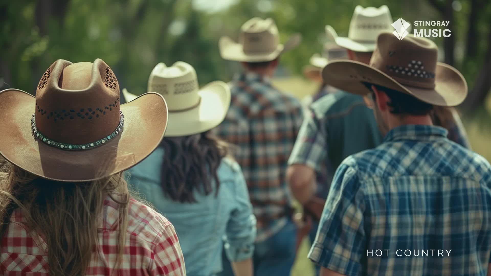 A group of people in cowboy hats and plaid shirts are walking away from the camera. The Stingray Hot Country logo is visible, and the scene appears to be outdoors in Canada.
