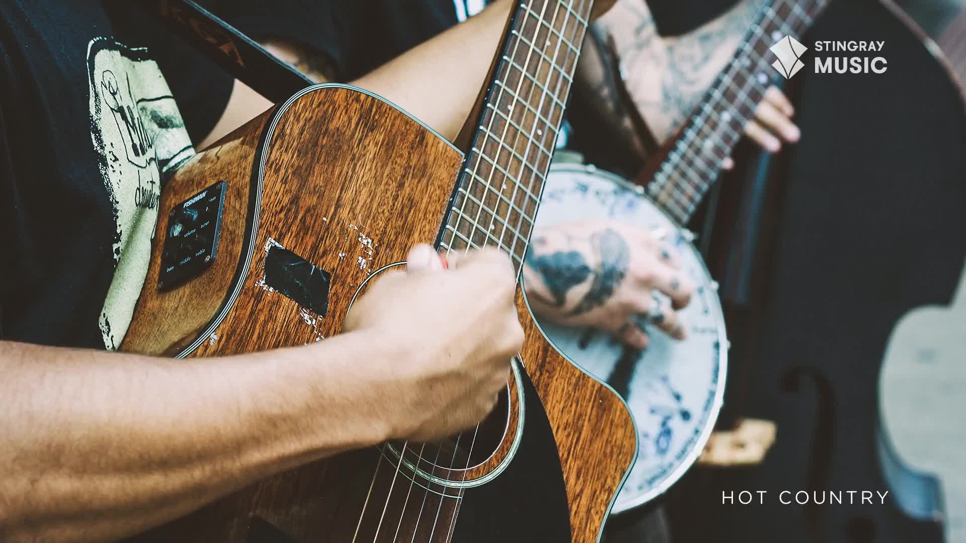 A guitarist's fingers dance across the frets of his acoustic, while a banjo player's tattooed hand strums alongside. The music, broadcast by Stingray Hot Country in Canada, is clear and vibrant.
