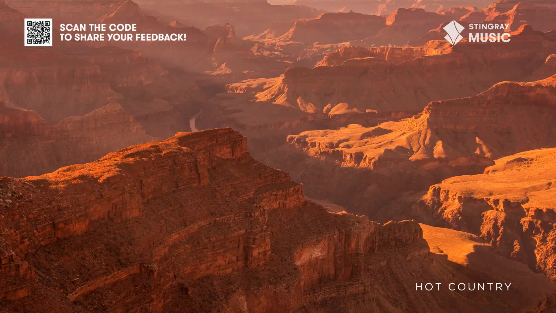 Sunlight bathes the canyon walls in a warm glow, highlighting the deep crevices and jagged edges. The Stingray Hot Country logo sits at the bottom, a reminder of the music that might accompany this breathtaking Canadian vista.
