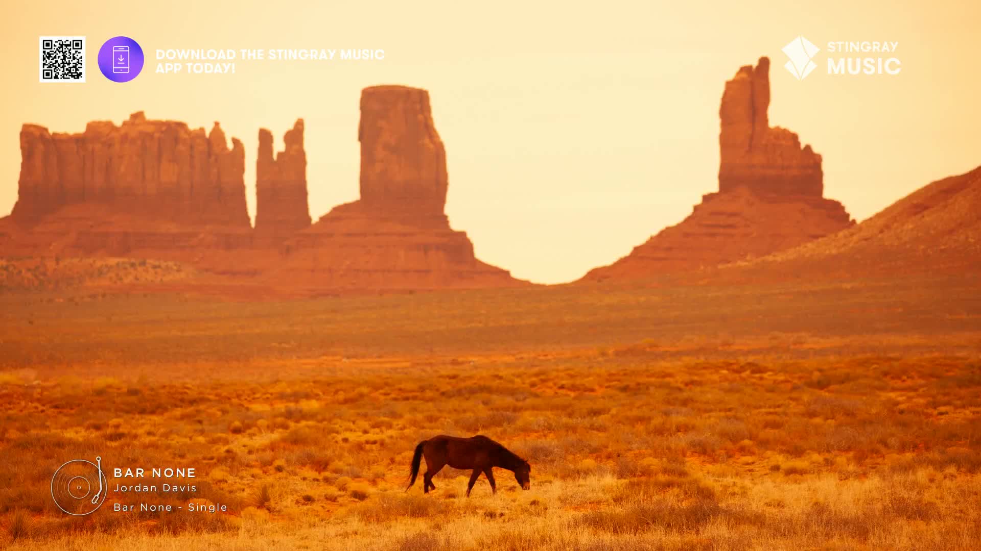 A lone horse grazes in a field, dwarfed by the towering rock formations in the distance. The Stingray Hot Country logo and a QR code sit in the top left corner, while the song "Bar None" by Jordan Davis is displayed at the bottom.
A lone horse grazes in a field, dwarfed by the towering rock formations in the distance. The Stingray Hot Country logo and a QR code sit in the top left corner, while the song "Bar None" by Jordan Davis is displayed at the bottom.