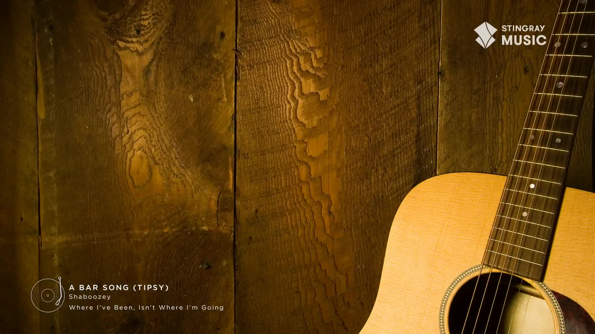 A wooden wall provides the backdrop for a Stingray Hot Country graphic. The neck of an acoustic guitar leans against the planks, its strings and soundhole visible.
A wooden wall provides the backdrop for a Stingray Hot Country graphic. The neck of an acoustic guitar leans against the planks, its strings and soundhole visible.