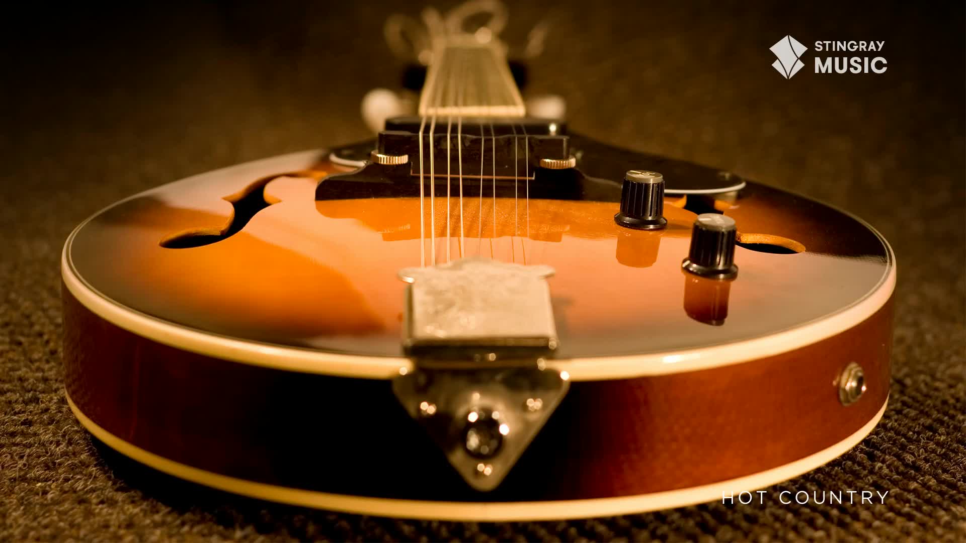 The sunburst finish on this hollow-body guitar gleams under the lights. Its strings are taut, ready for a country tune from Stingray Hot Country.