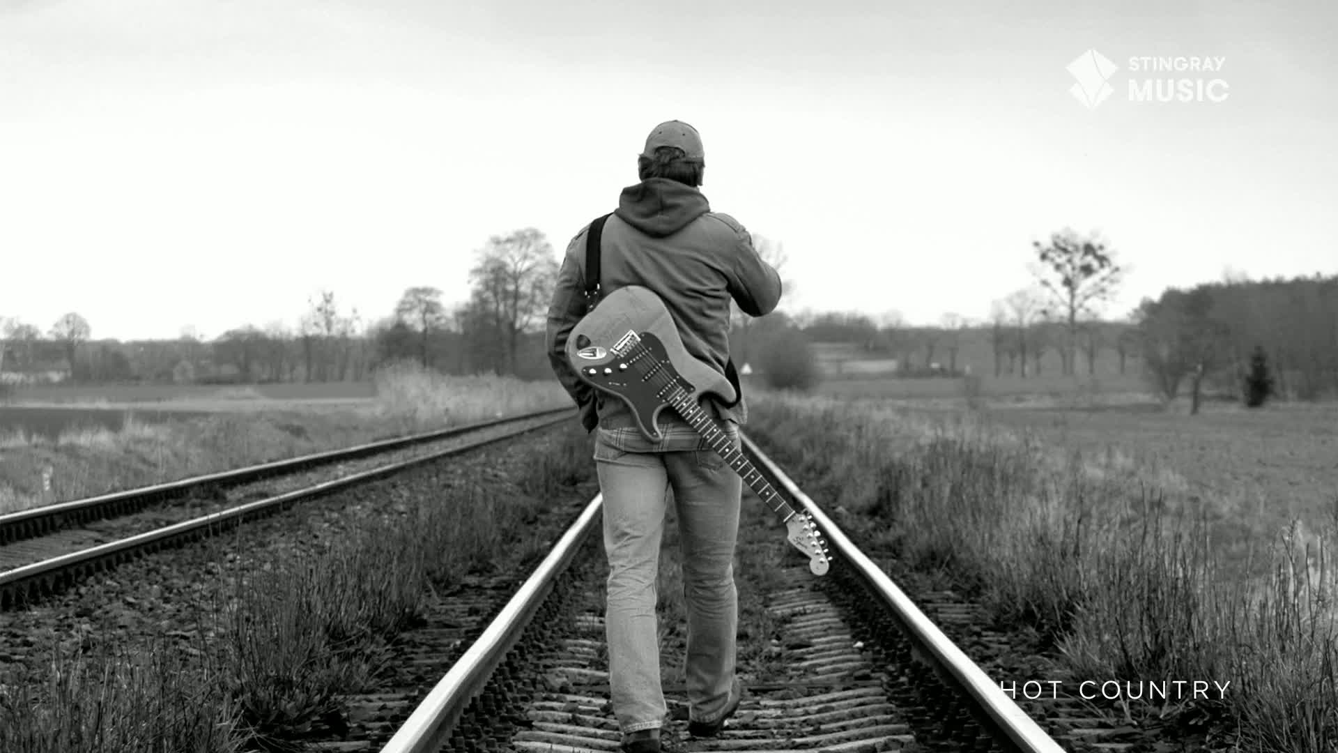 A lone figure walks down the train tracks, an electric guitar slung over his shoulder. The wide-open Canadian landscape stretches out behind him, hinting at the journey ahead.