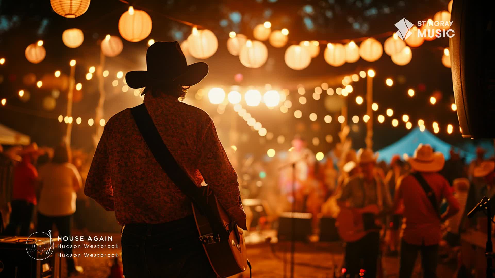 A musician in a cowboy hat strums his guitar, facing a crowd gathered under strings of glowing lanterns. The air buzzes with the energy of a Canadian country music festival.