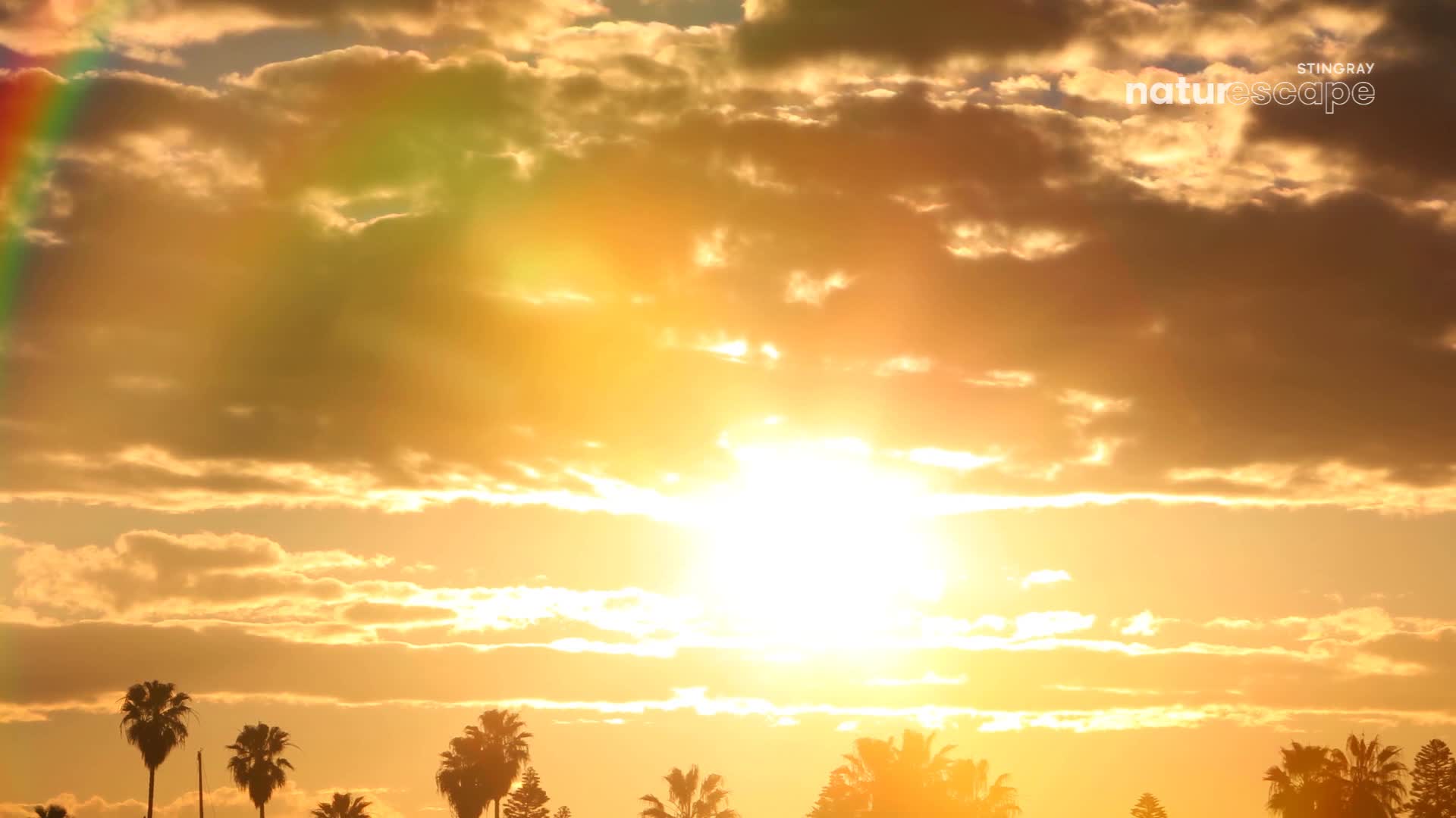 The sun blazes, a bright orb behind the clouds. A faint rainbow arcs across the sky, its colors muted by the golden light.
