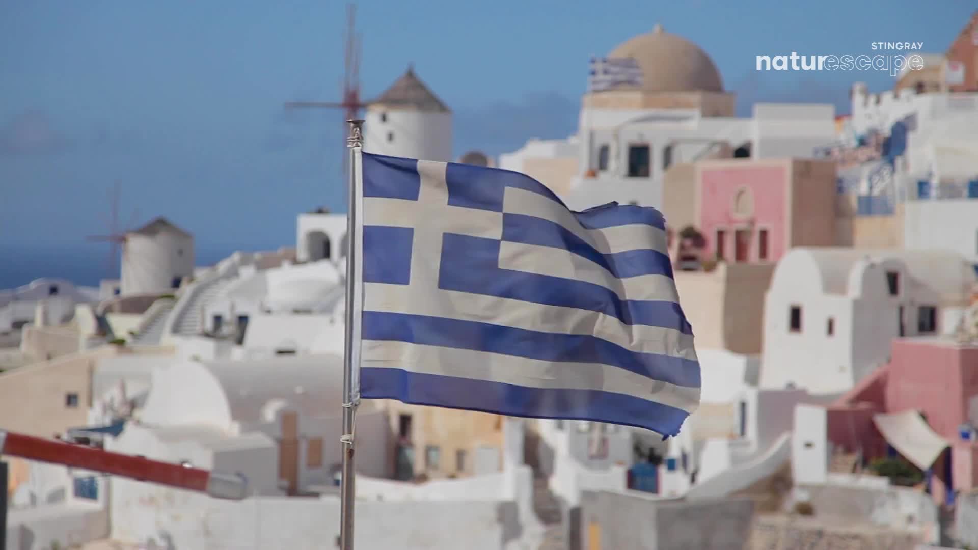 The Greek flag snaps in the breeze against a backdrop of whitewashed buildings and windmills. The blue and white stripes ripple, catching the sunlight as the village sprawls across the hillside. The Greek flag snaps in the breeze against a backdrop of whitewashed buildings and windmills. The blue and white stripes ripple, catching the sunlight as the village sprawls across the hillside.