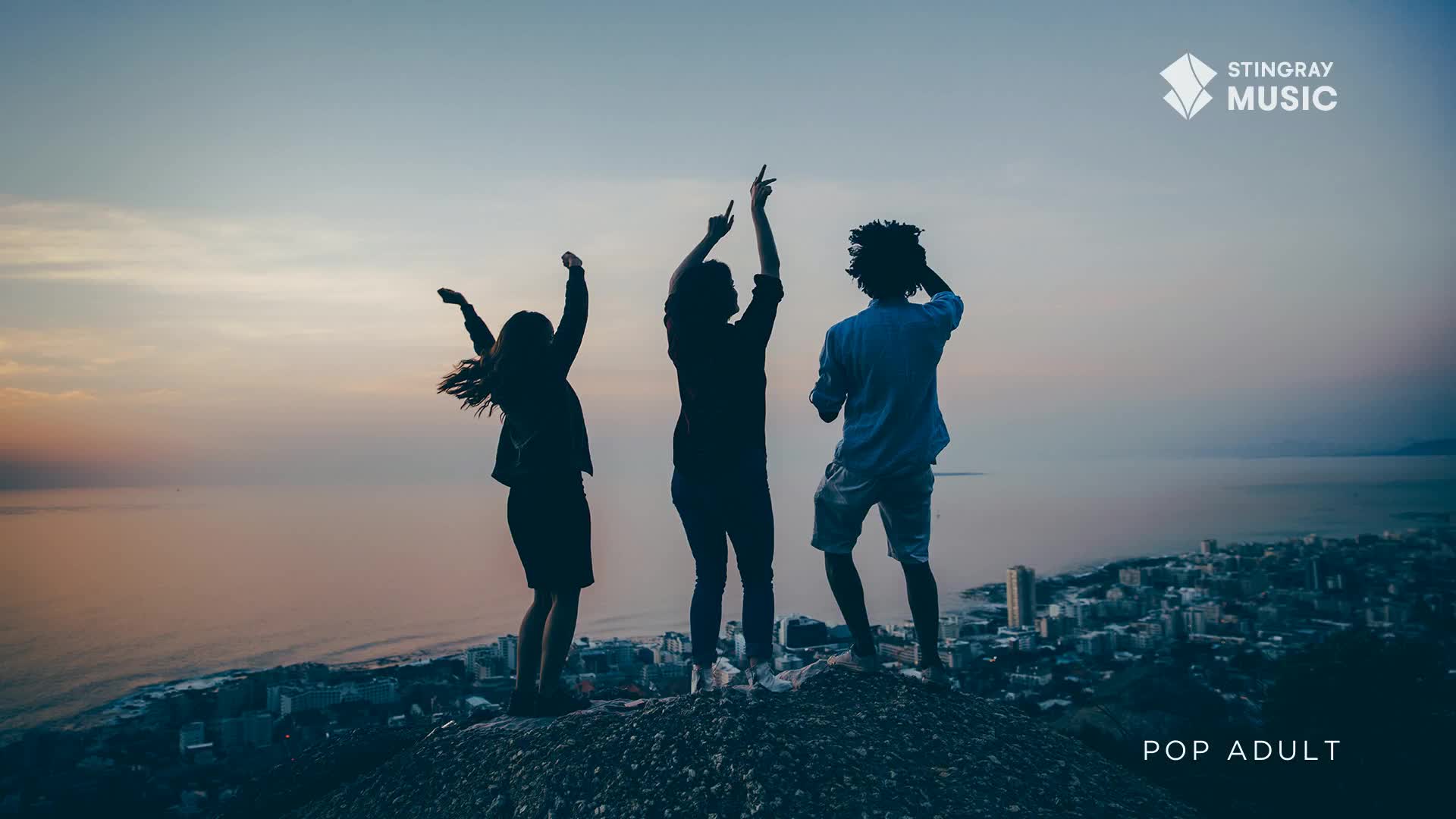 Three people are silhouetted against the dusky sky, arms raised and bodies swaying on a hilltop overlooking a city. The Stingray Music logo and "Pop Adult" text suggest they're celebrating a great song from Canada.
