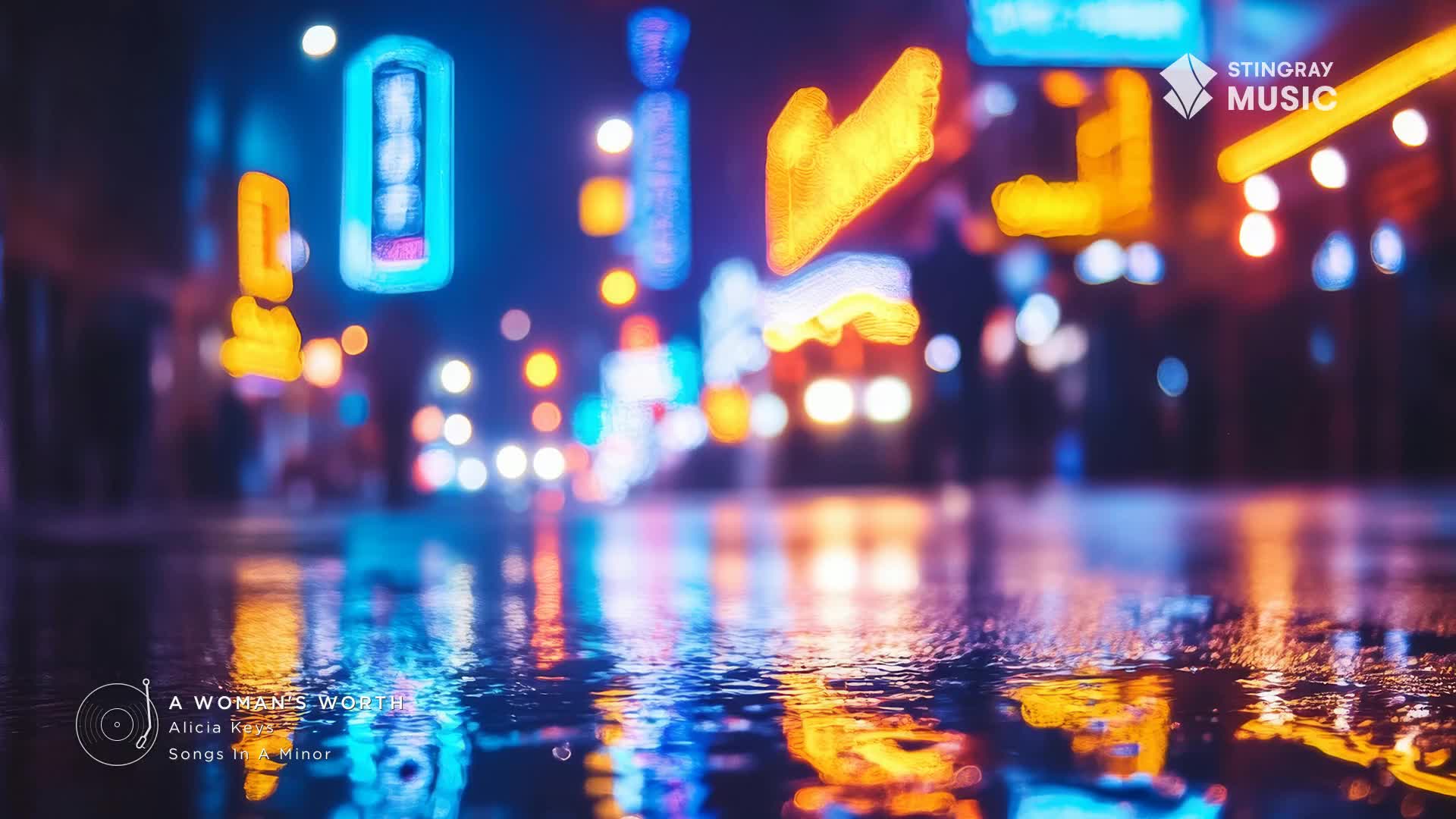 The wet street reflects the neon lights of the city, creating a shimmering, colorful mirror.  A Stingray Music logo sits in the corner, promoting Alicia Keys' "A Woman's Worth" on Stingray Pop Adult.
