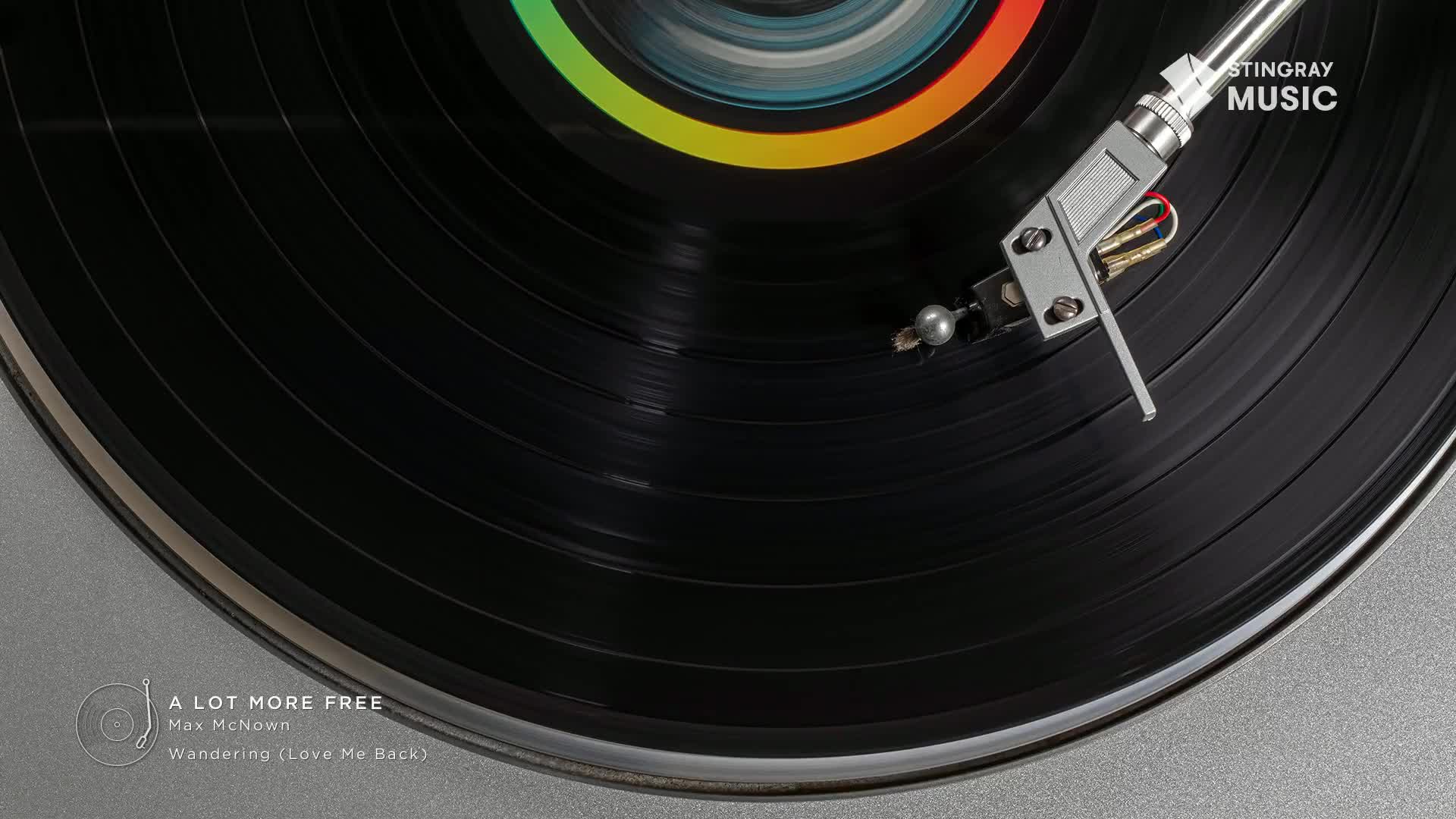 A black vinyl record spins, the needle resting gently in the grooves. The Stingray Music logo is visible, and the album is "A Lot More Free" by Max McNown.
