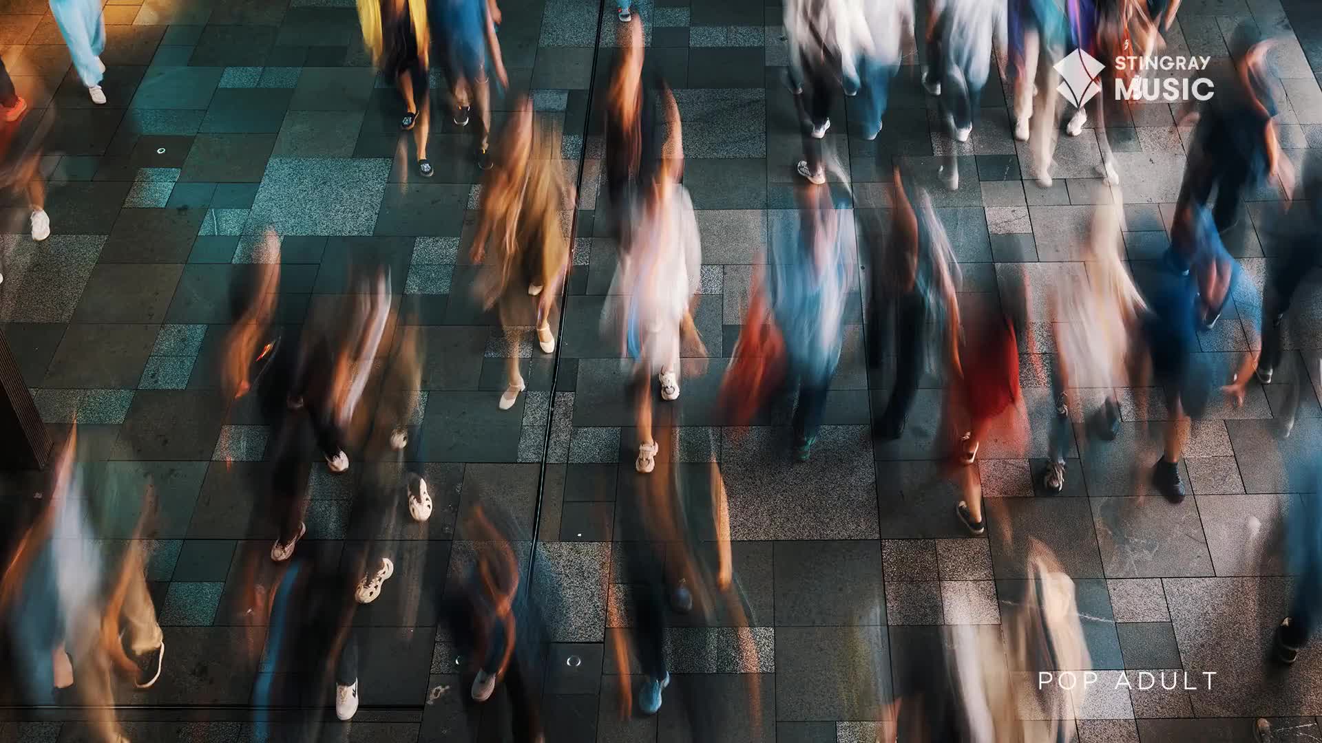 A crowd moves across a patterned walkway, their forms streaked with motion. The Stingray Music logo appears over the heads of people walking.