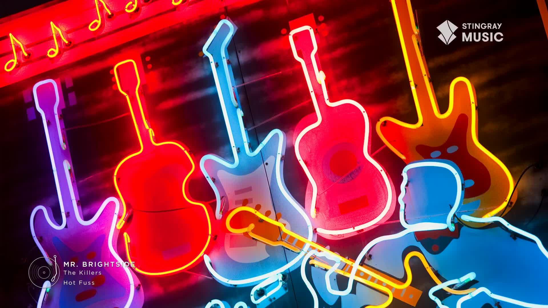 Neon guitars glow in vibrant reds, blues, and purples against a dark sky. A silhouette of a guitarist, outlined in bright blue and yellow, stands in front of the luminous instruments.