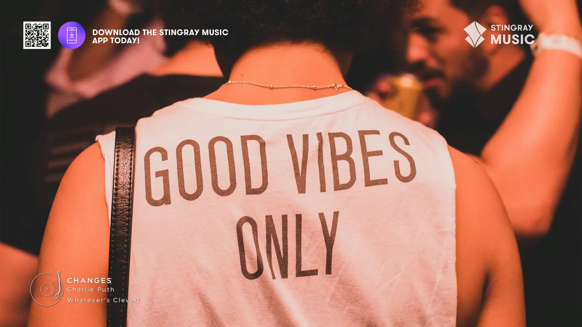 The crowd is packed in, the music pulsing through the air. A woman in a white tank top that reads "GOOD VIBES ONLY" is moving with the rhythm.