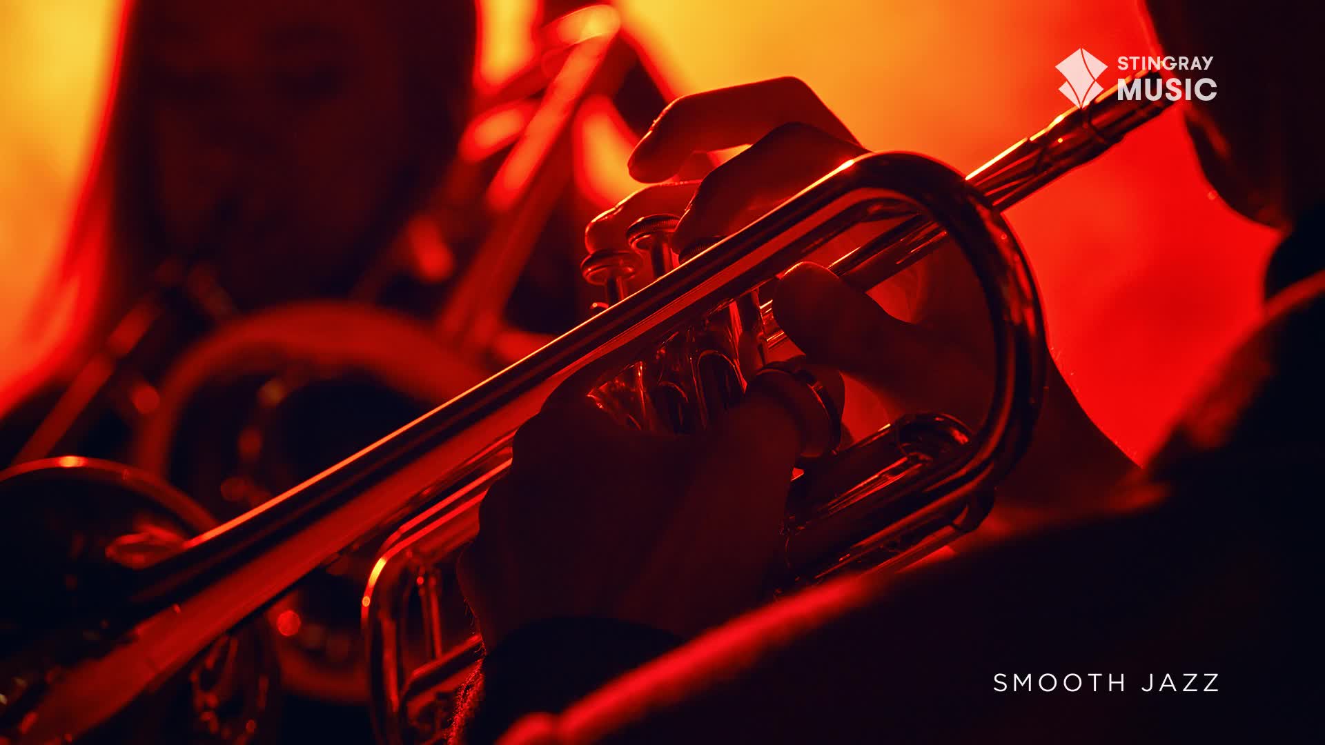A musician's hands cup a gleaming trumpet, the instrument catching the warm, red light.  The sound of smooth jazz, broadcast from Canada, fills the air.
