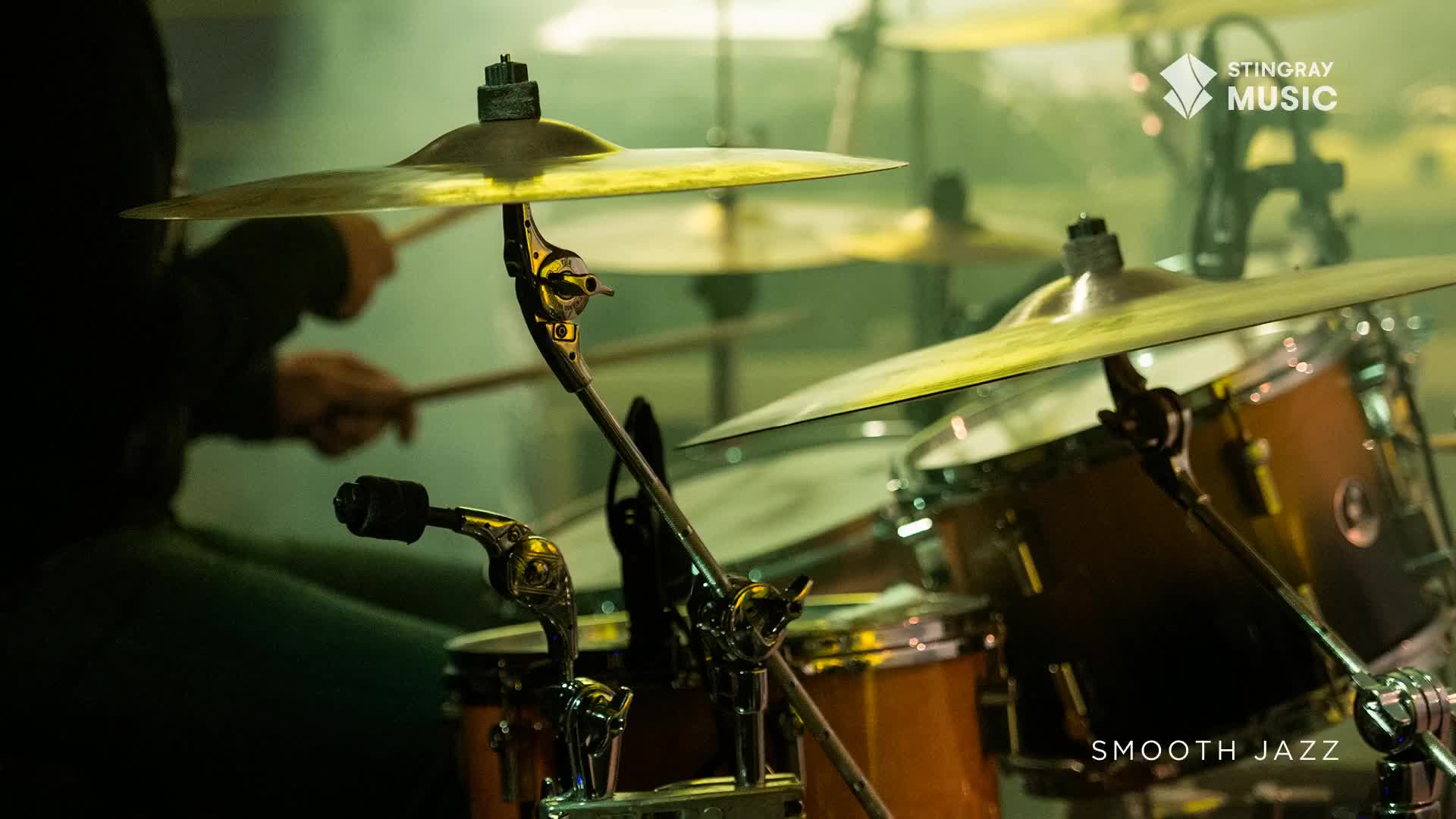 The drummer's arms are a blur as he hits the cymbals, their golden surfaces catching the light. It's a Stingray Smooth Jazz session, and the drums are the heart of the sound.
