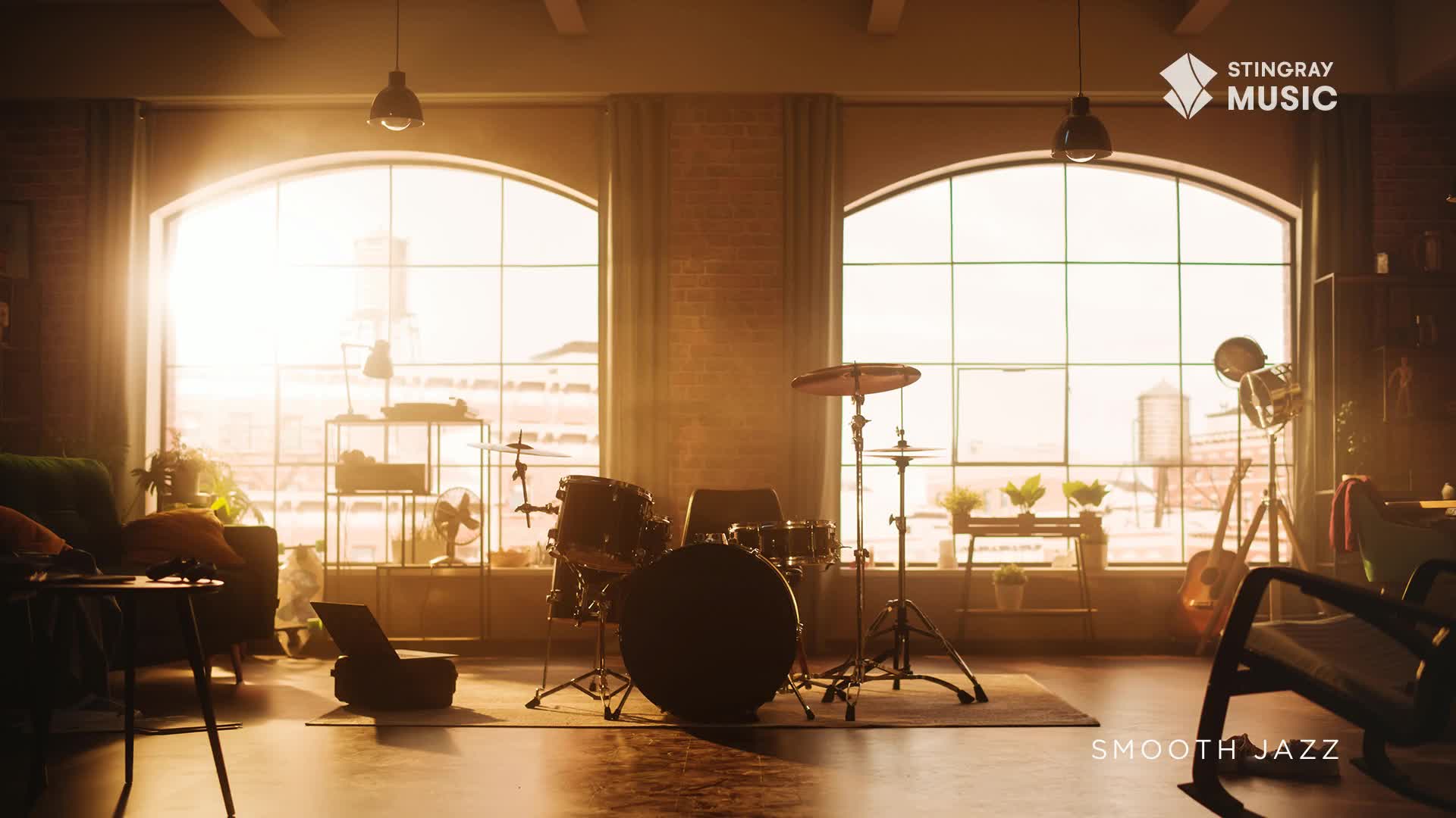 Sunlight streams through the arched windows of a loft, illuminating a drum kit set up on a rug. The scene evokes a warm, relaxed vibe, perfect for Stingray Smooth Jazz, a Canadian favourite.
