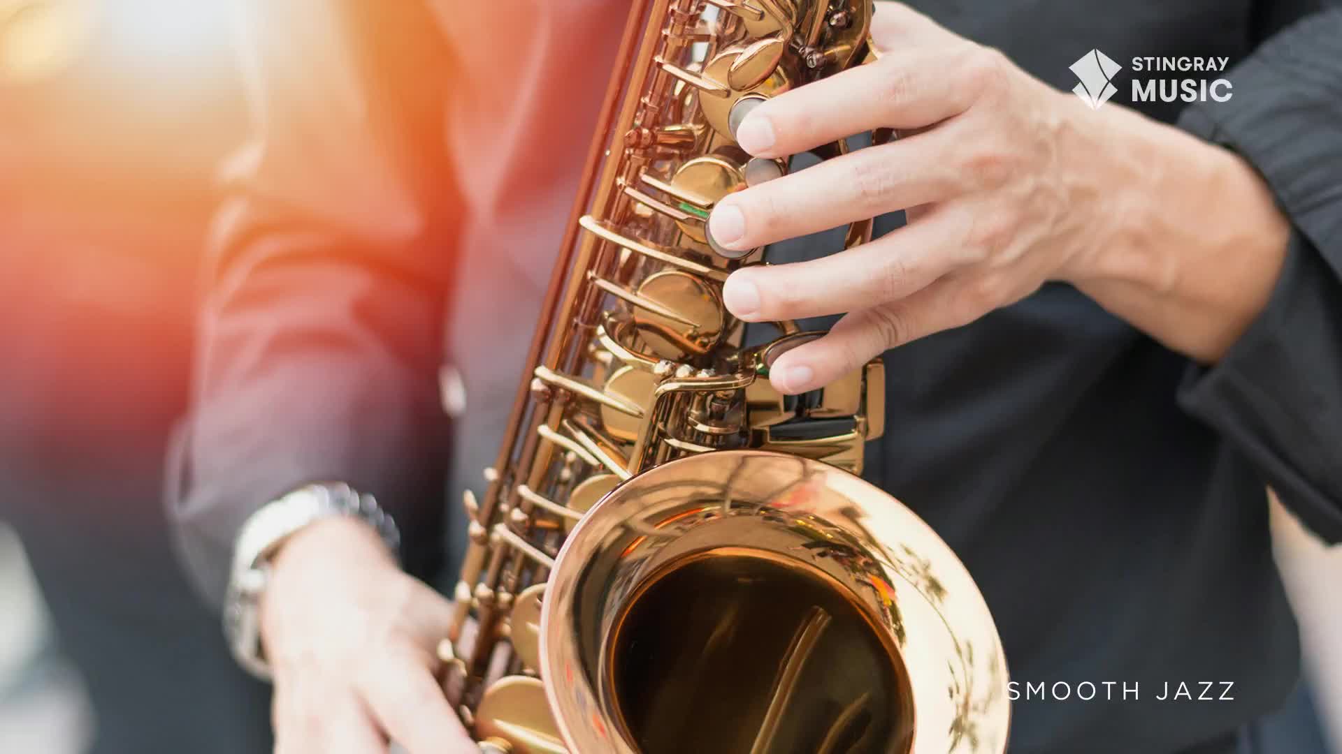 A musician's hands grip a golden saxophone, fingers poised over the keys. The instrument gleams in the light, ready to play some smooth jazz, perhaps from Stingray Music.

