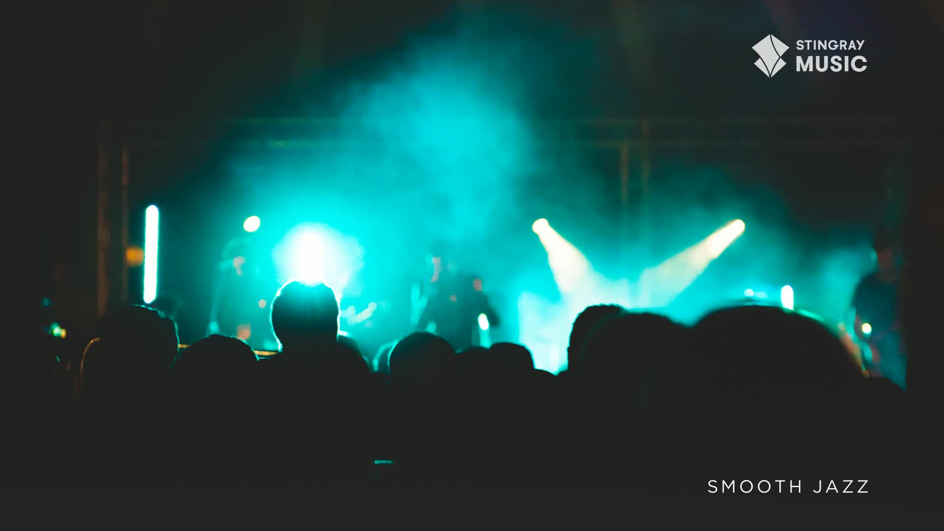 The stage is bathed in a cool, blue light, and the band is silhouetted against it.  A crowd of people are swaying, lost in the smooth jazz emanating from the speakers.

